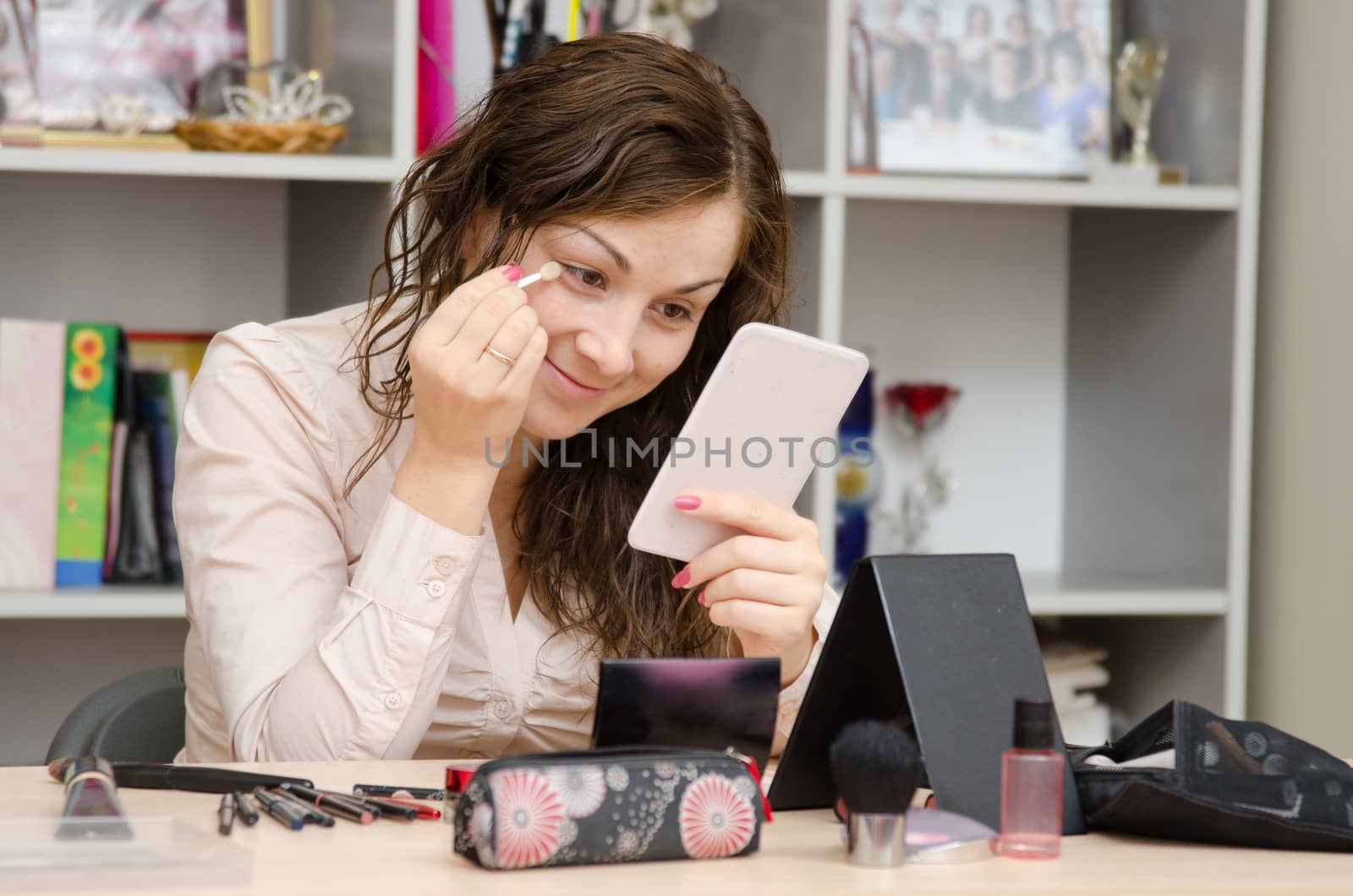 Young girl puts makeup in the office workplace