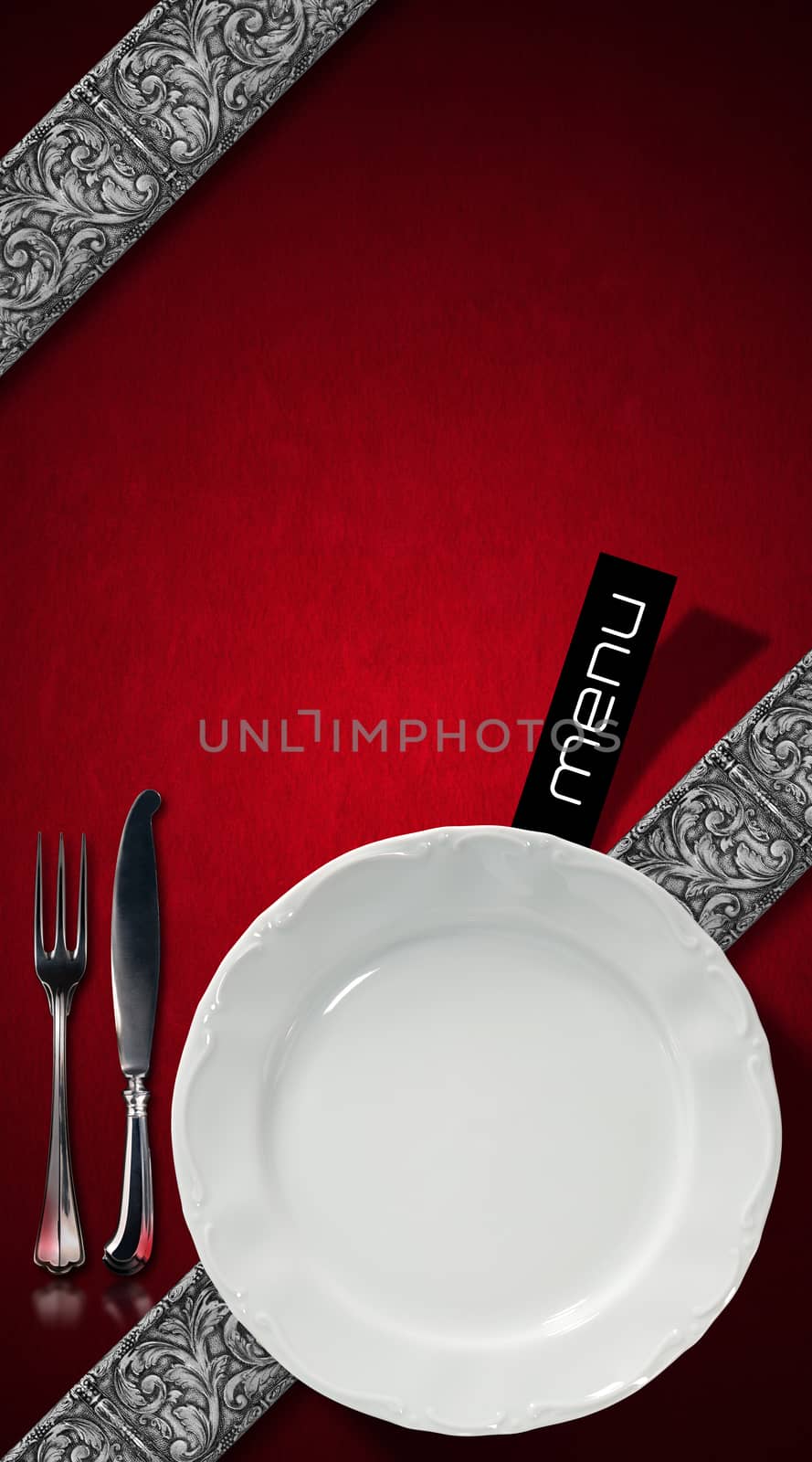 Red velvet background with diagonal silver floral bands, empty white plate and silver cutlery. Template for an elegant restaurant menu