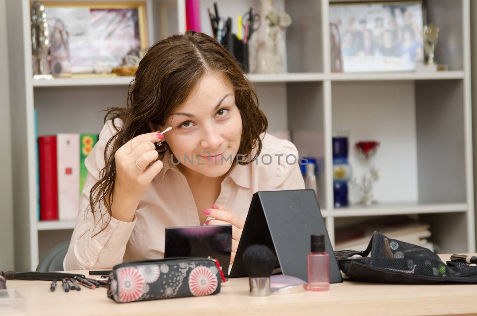 A young girl puts makeup in the office workplace