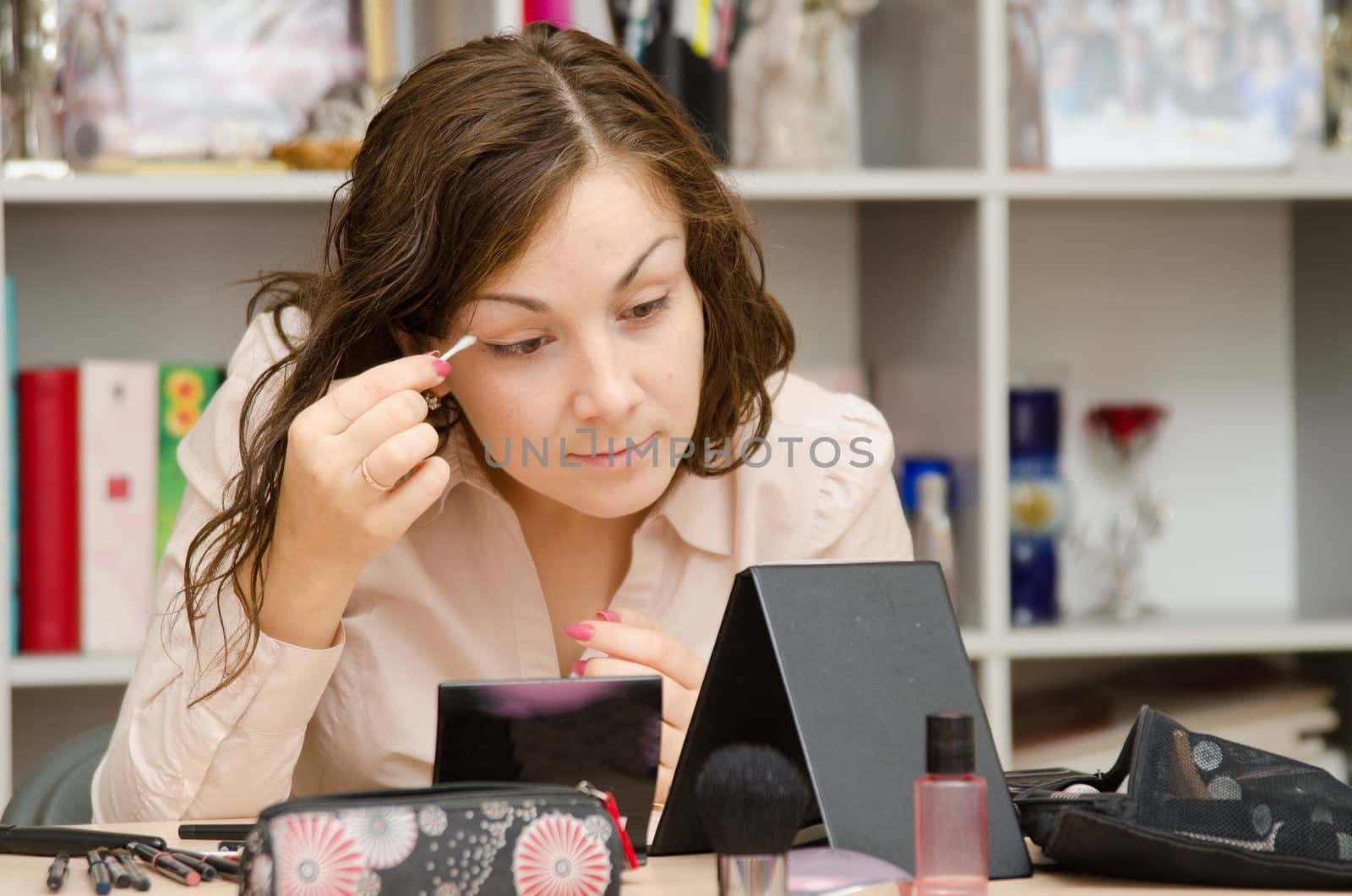 A young girl puts makeup in the office workplace
