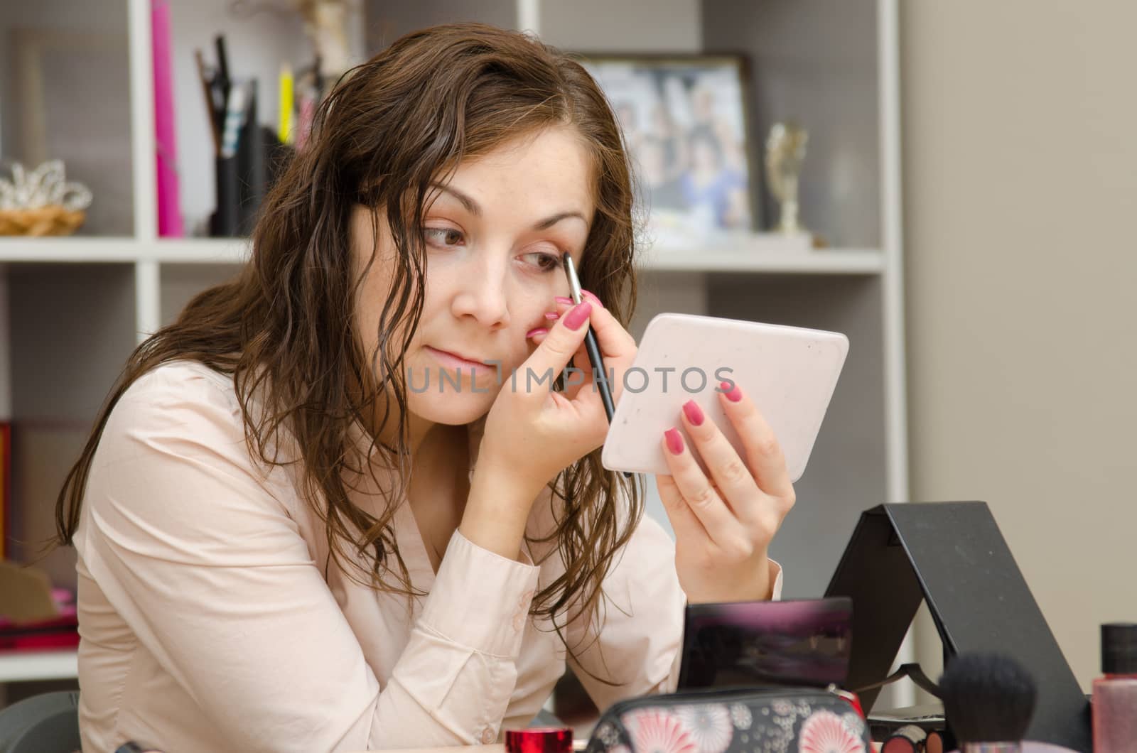 A young girl puts makeup in the office workplace