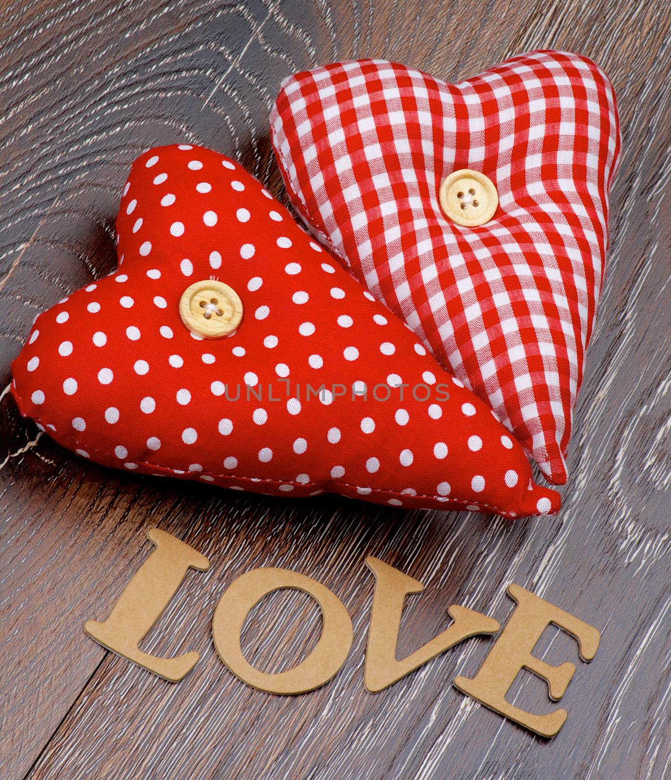 Cardboard Word Love and Two Handmade Textile Red Polka Dot Hearts closeup on Hardwood background
