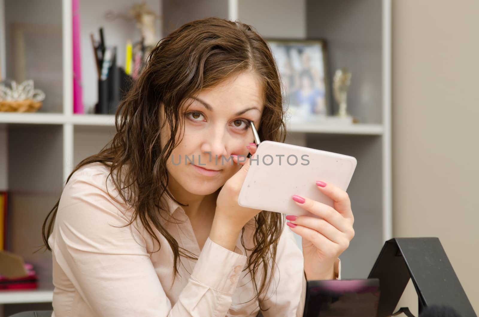 A young girl puts makeup in the office workplace