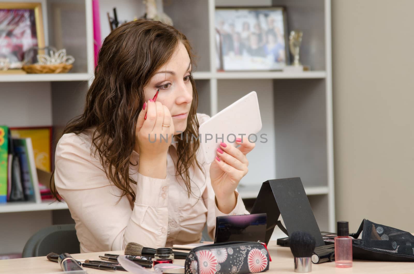 A young girl puts makeup in the office workplace
