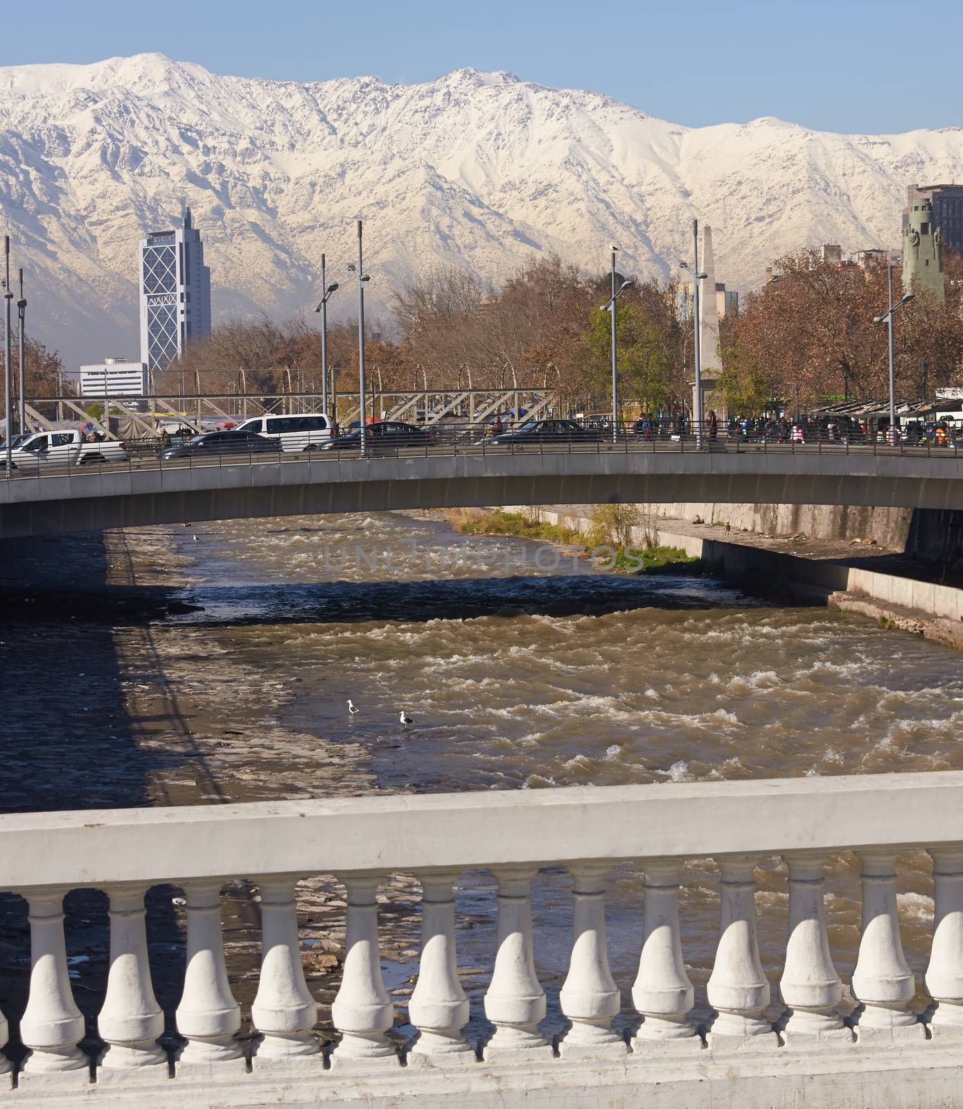 Snow covered mountains surrounding the city of Santiago, capital of Chile. View from a bridge across the Mapocho River in central Santiago.