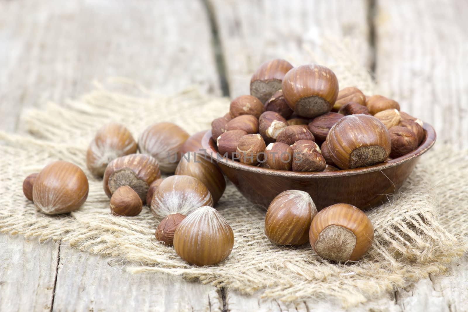 hazelnuts in a bowl on old wooden background by miradrozdowski