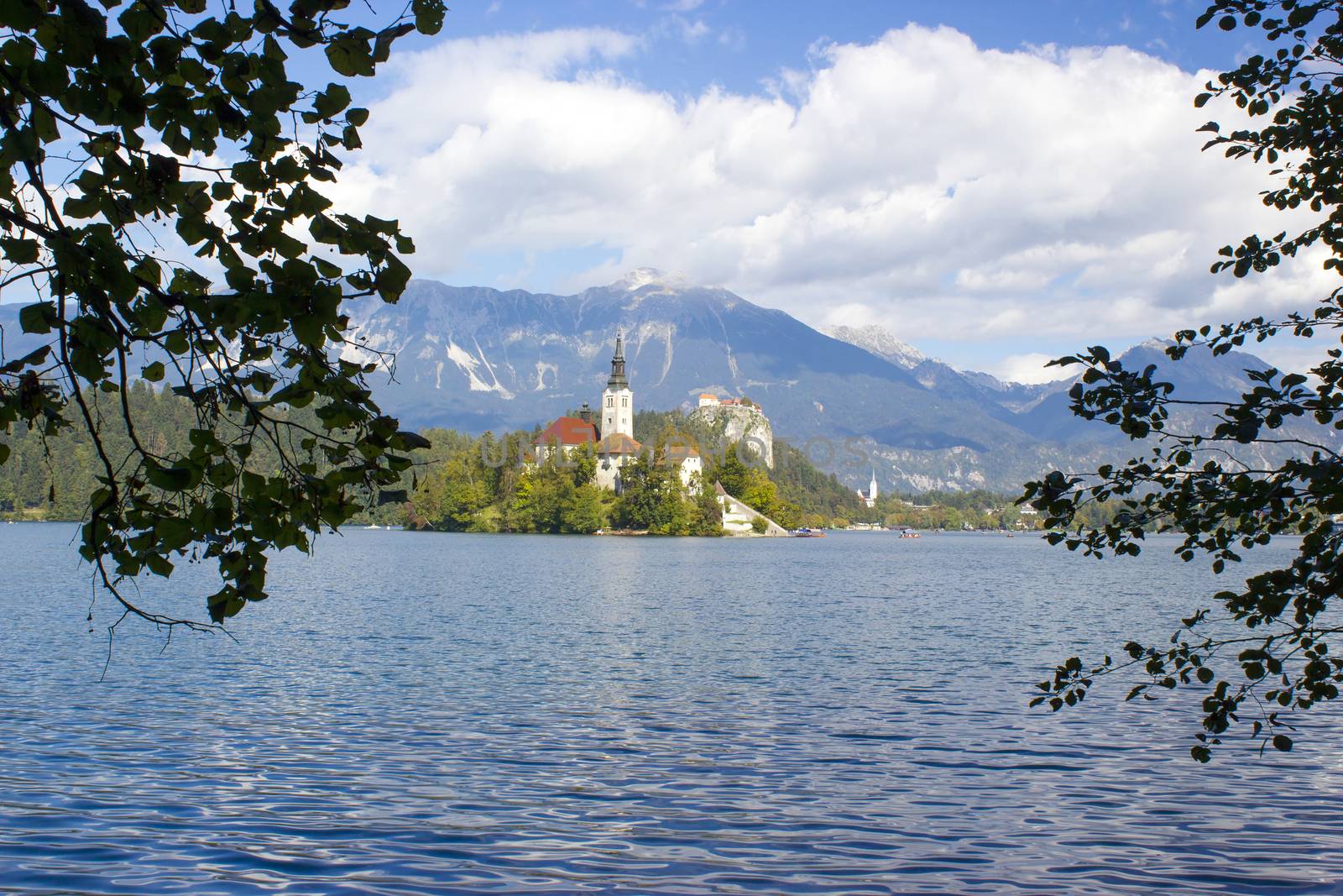 Catholic church situated on an island on Bled lake with mountains on the background 