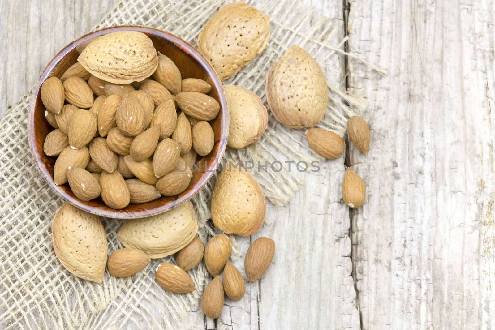 almonds in a bowl on old wooden background by miradrozdowski