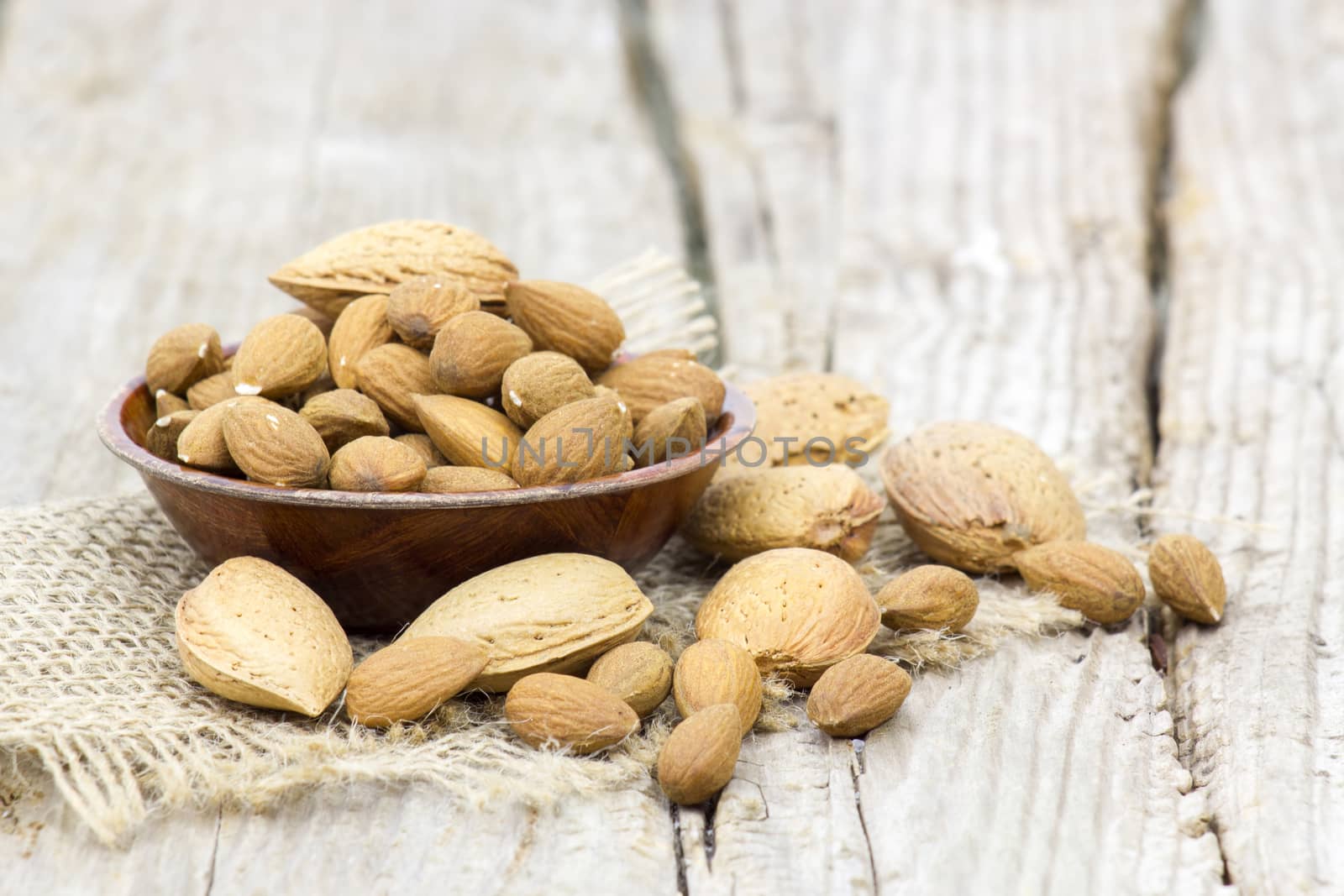 almonds in a bowl on old wooden background