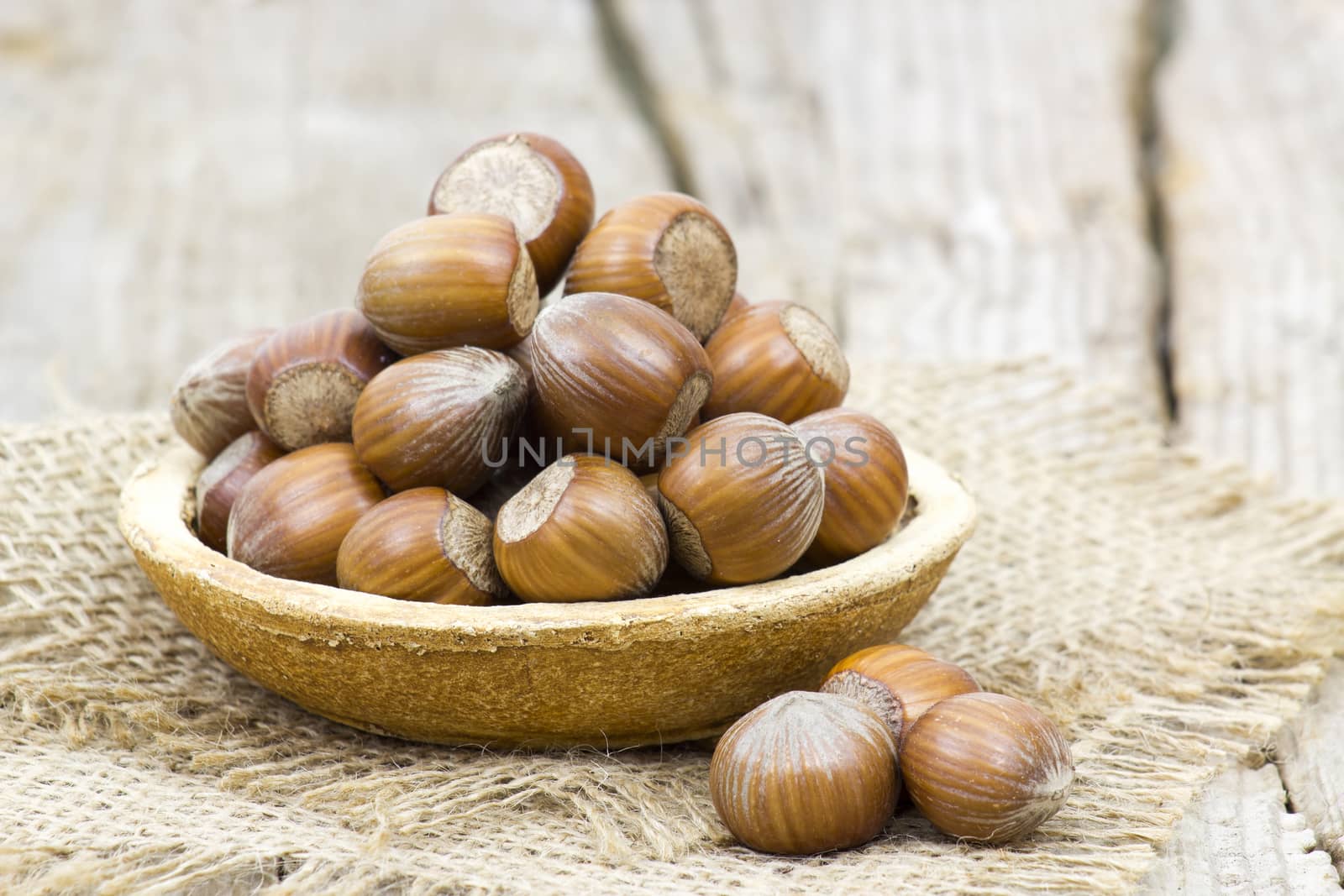 hazelnuts in a bowl on old wooden background by miradrozdowski