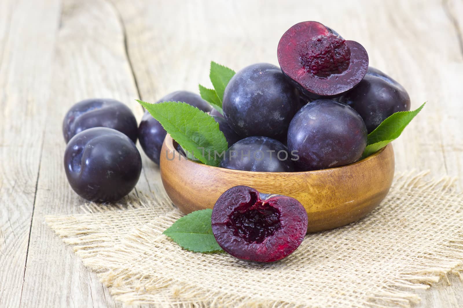 fresh plums in a bowl on old wooden background