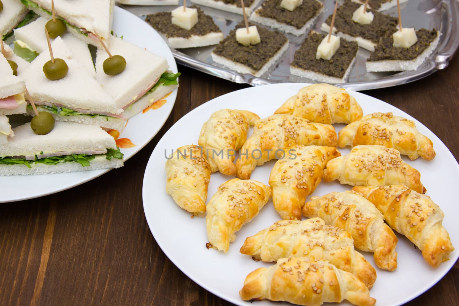 Croissants and other appetizers on wooden table seen up close