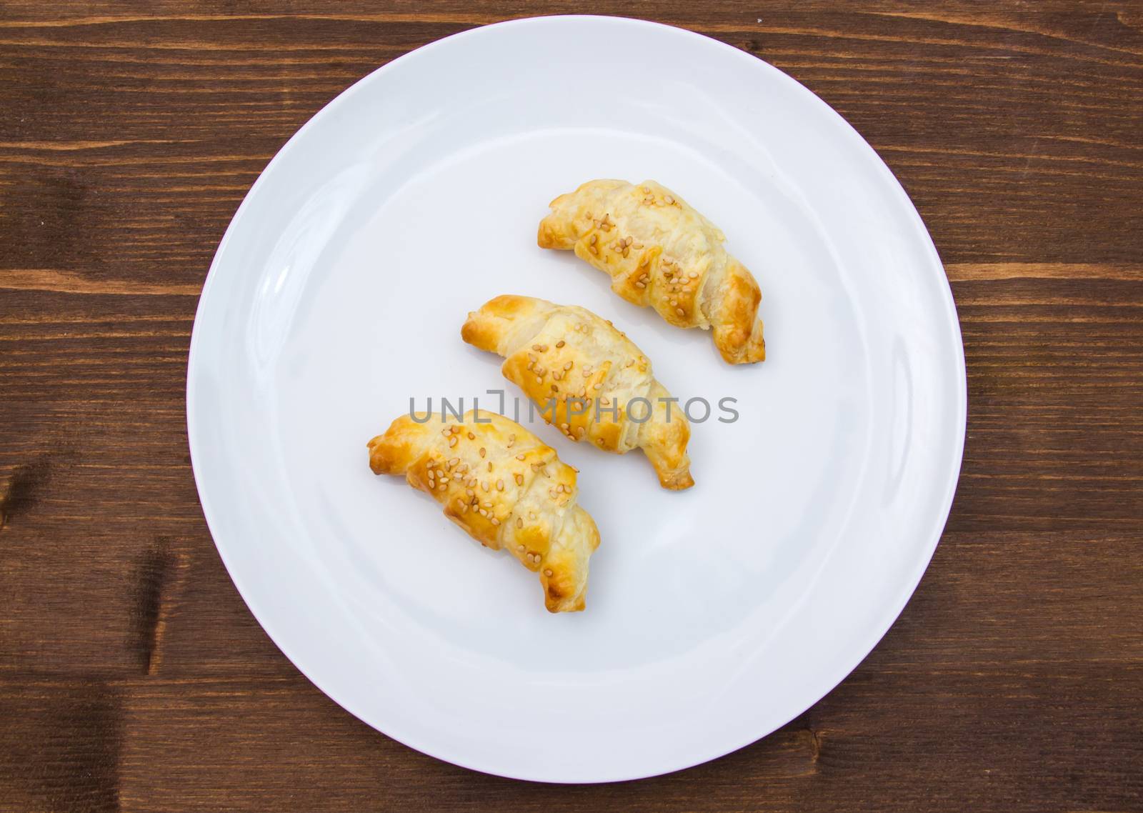 Savory croissants with sesame on wooden table seen from above