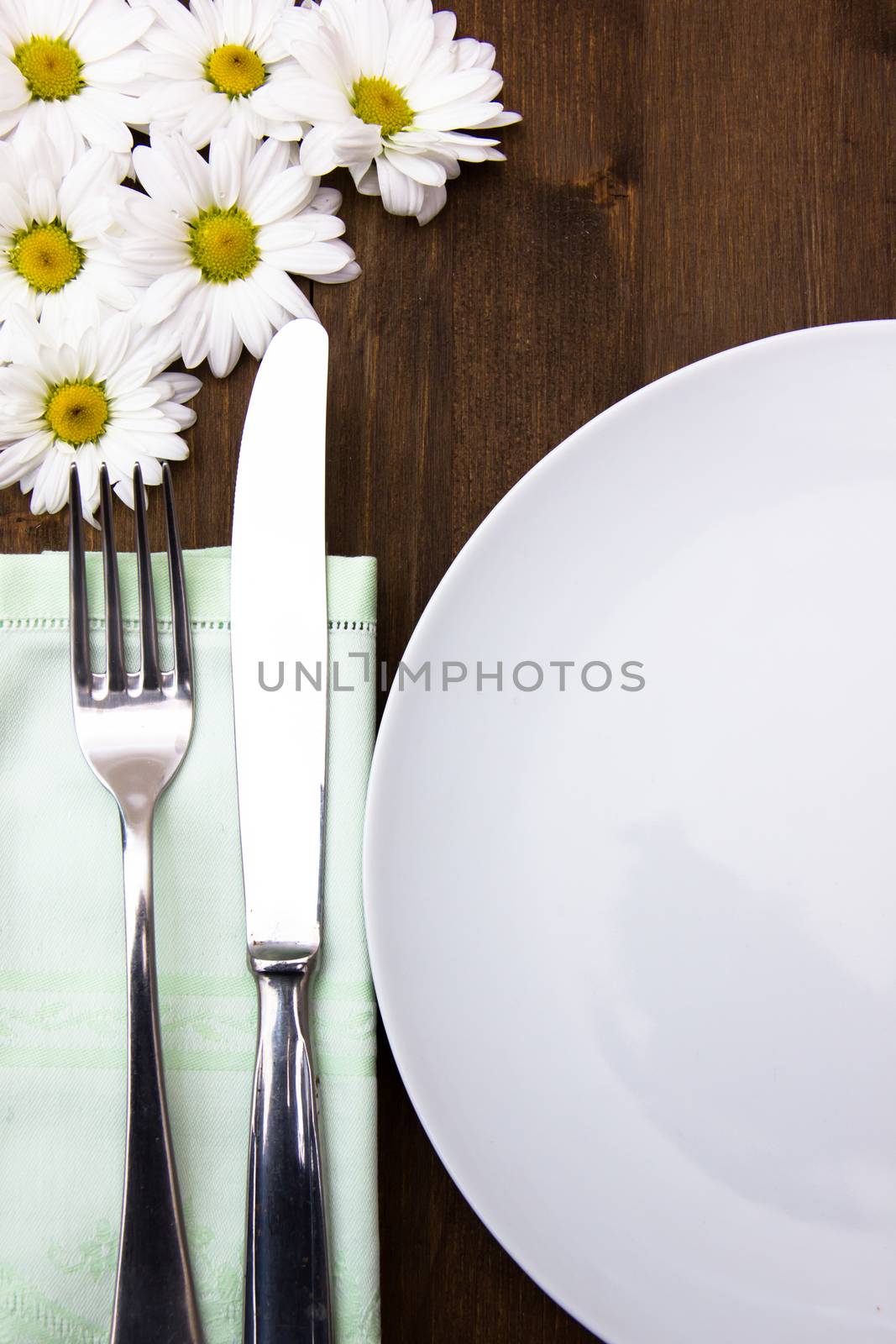 Cutlery and plate with flowers on wooden table