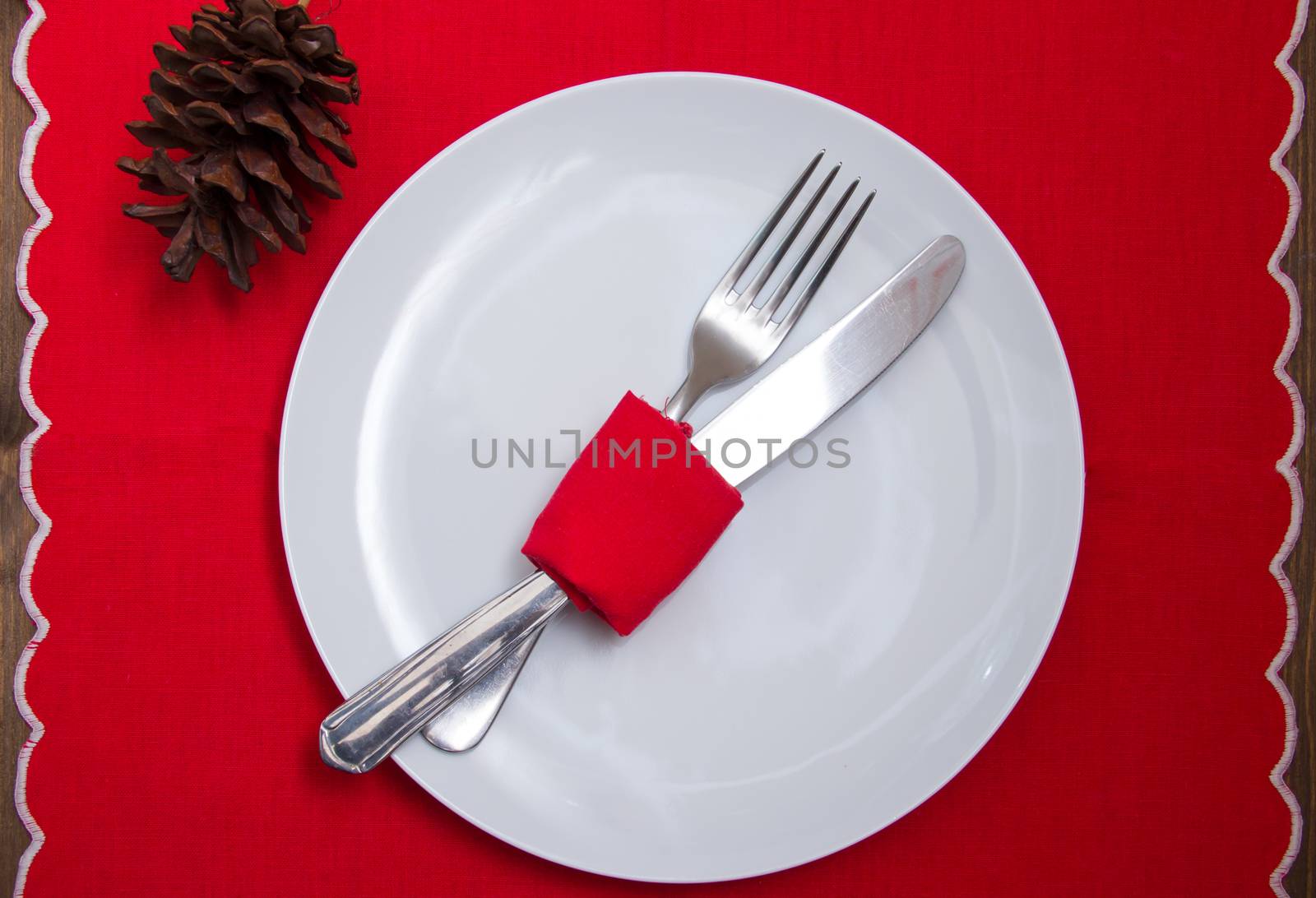 Cutlery wrapped with napkin on plate with Christmas decorations