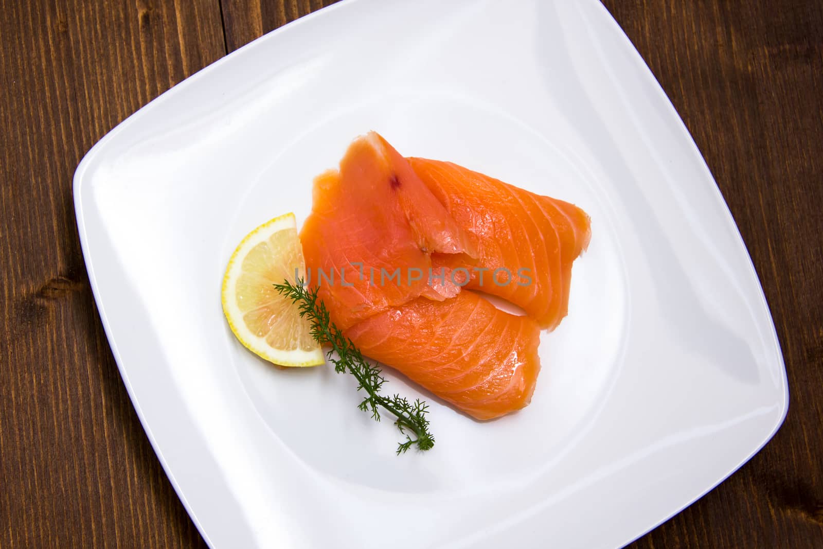 Smoked salmon on plate on wooden table seen from above