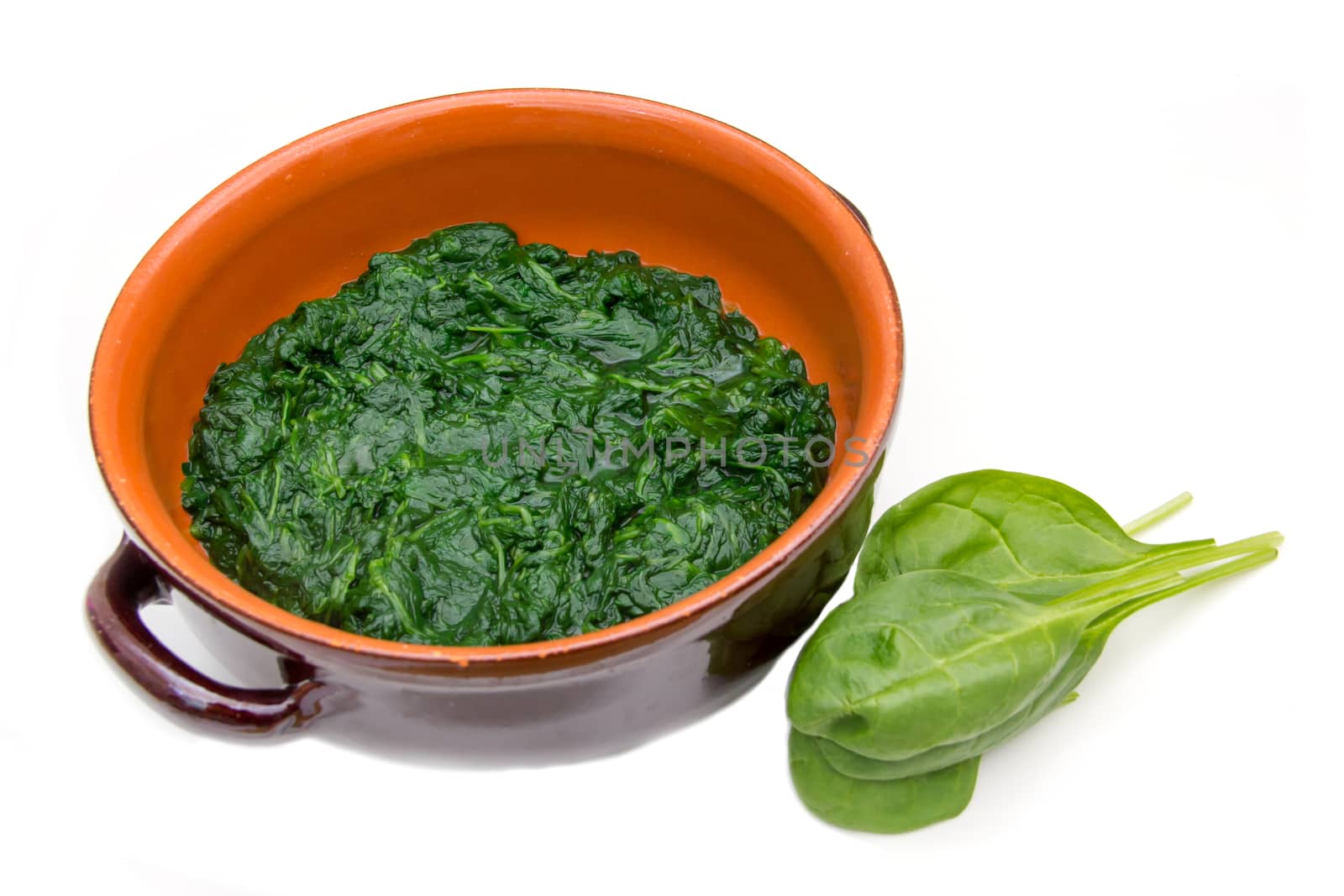 Spinach cooked in the pan on a white background