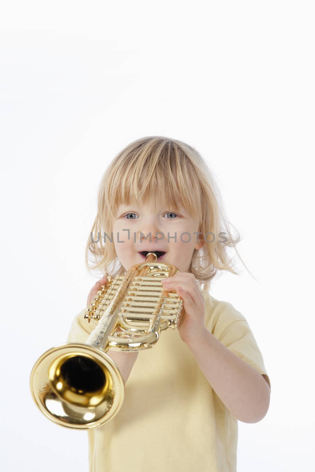 boy with long blond hair playing with toy trumpet