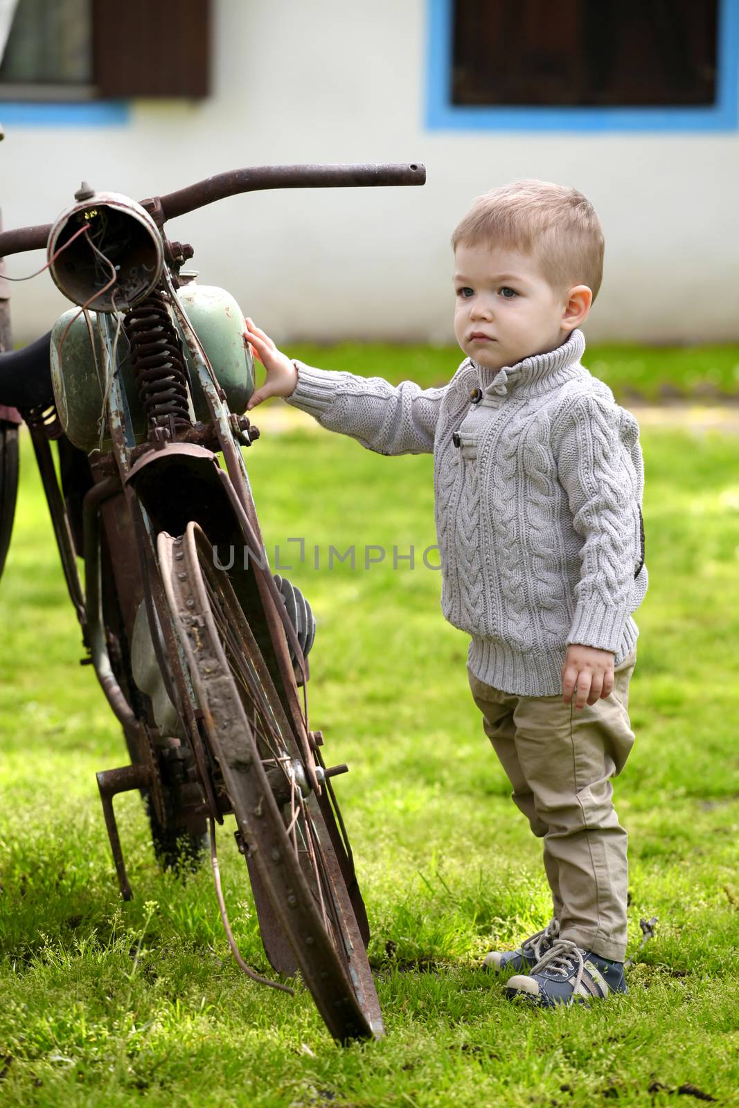 2 years old curious Baby boy walking around the old bike 
