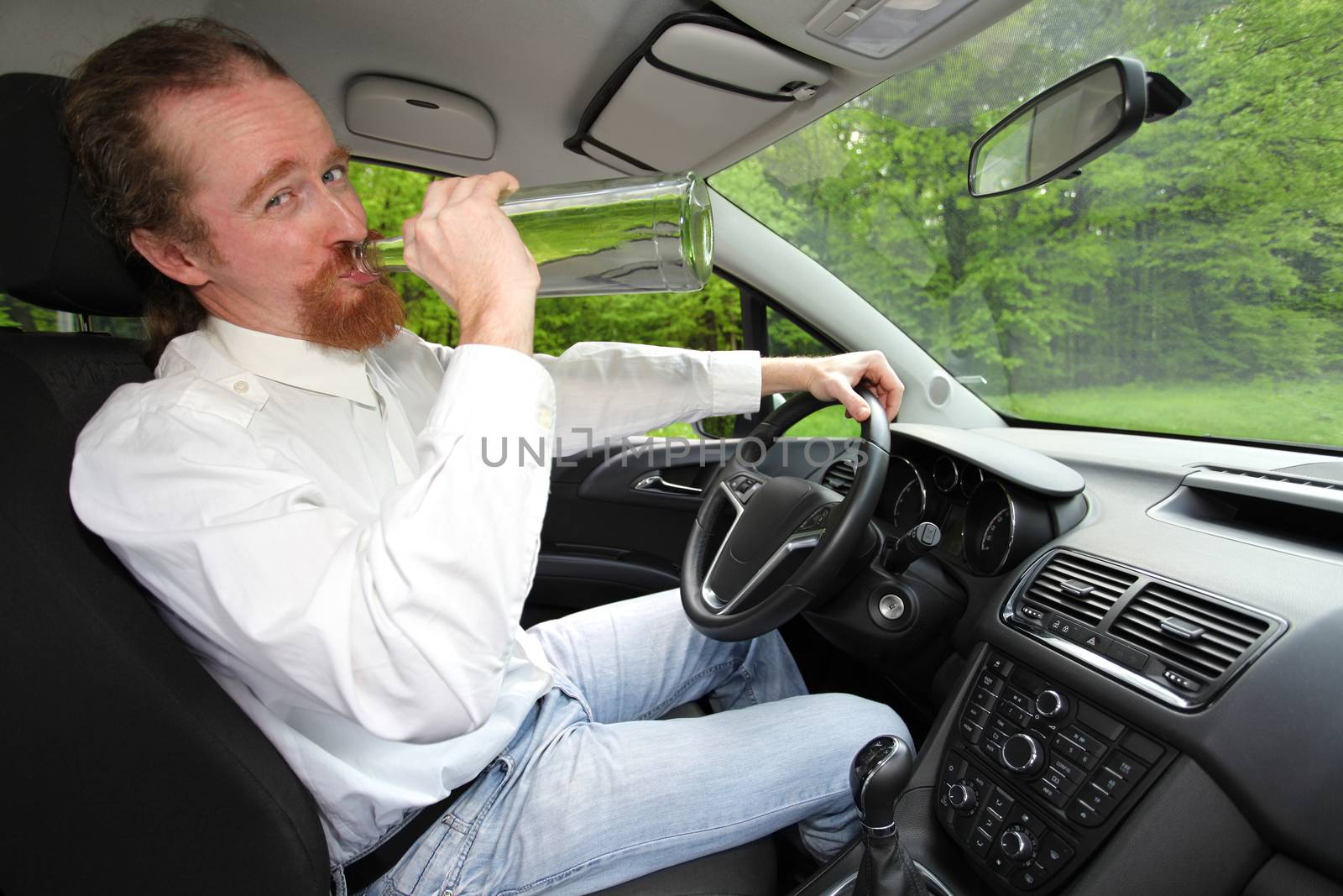 Drunk man in car with a bottle alcohol
