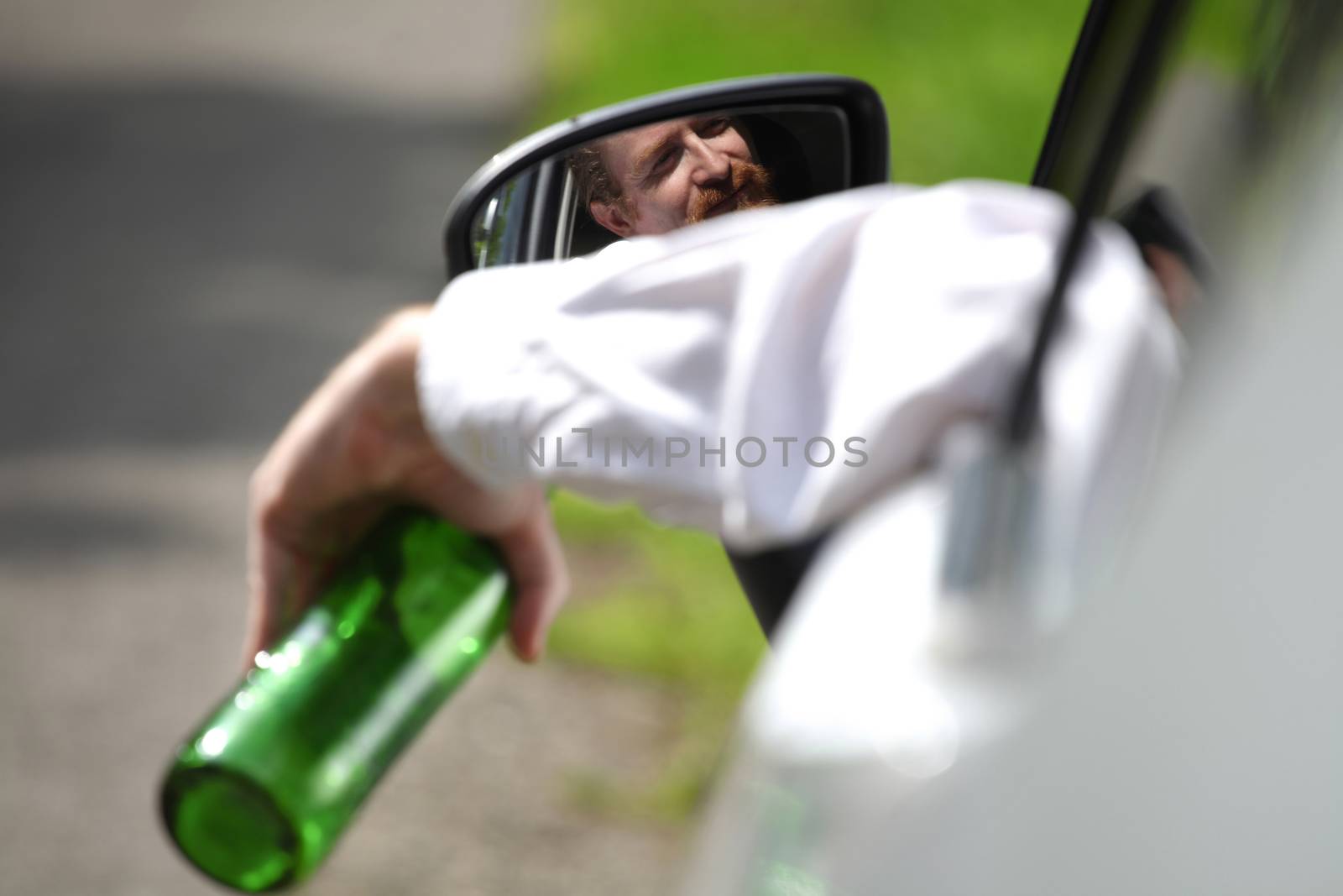 Drunk man in car with a bottle alcohol by vladacanon