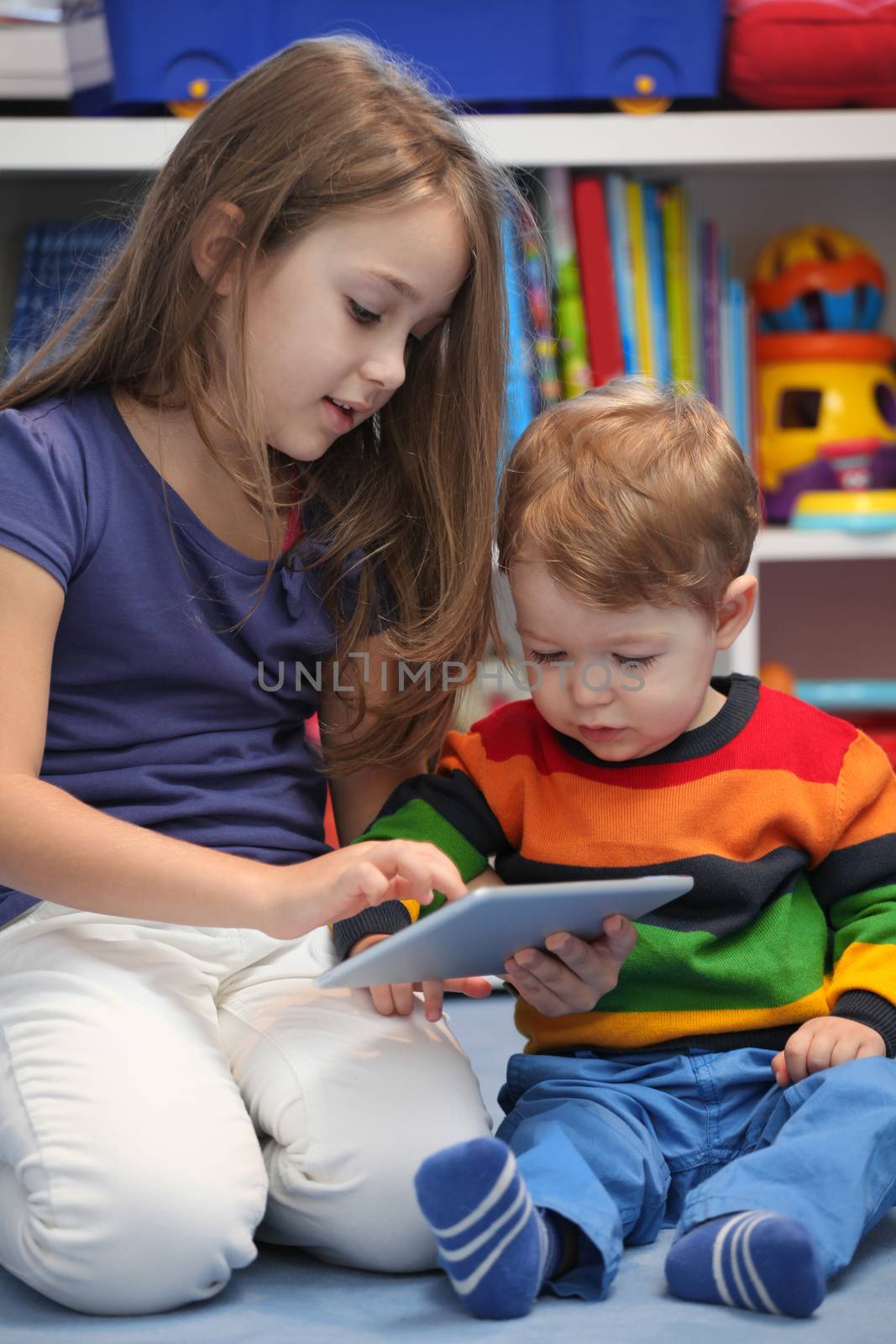 Girl with her little brother fun using a digital tablet computer by vladacanon