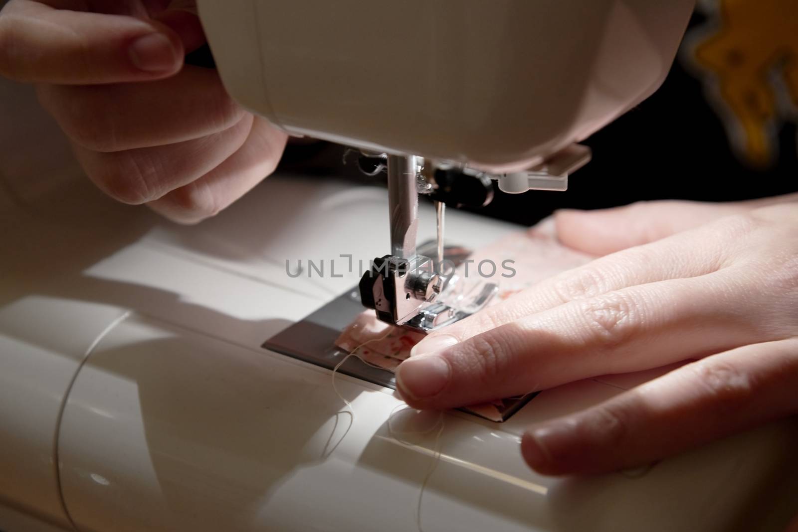 Detail of hands working on piece of fabric on automatic sewing machine