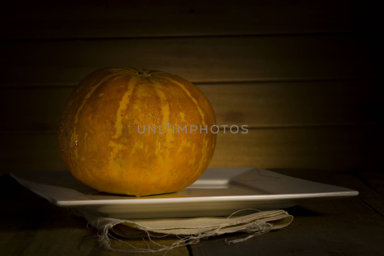 Thai cantaloupe melon or sweet melon on a table in front of a wooden wall