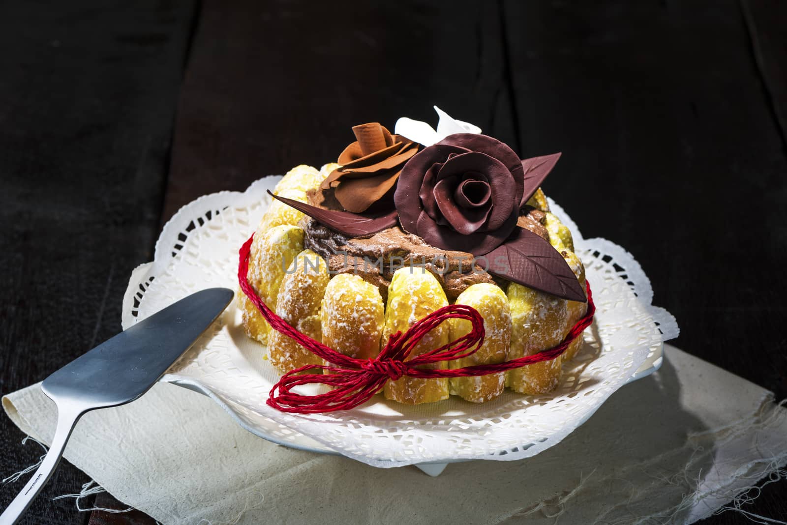 Beautifully decorated chocolate cake topped with roses on cocoa icing and surrounded with freshly baked golden pastries for a delicious dessert or sweet