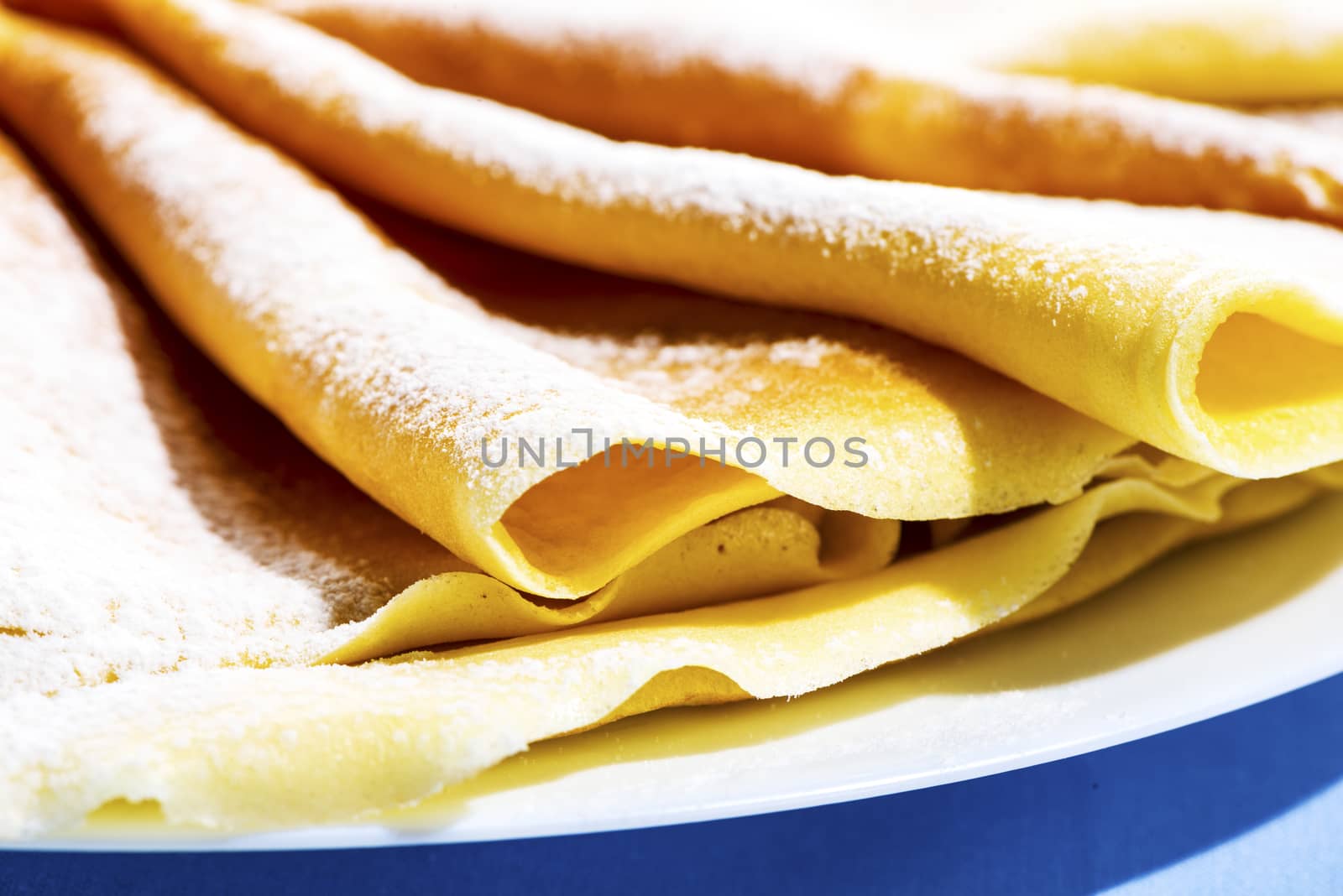 Freshly baked golden pancakes or crepes neatly folded in a plate