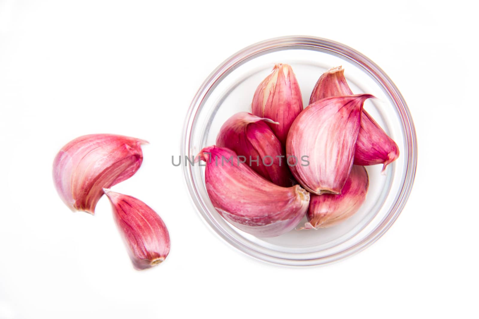 Garlic in glass bowl on a white background seen from above