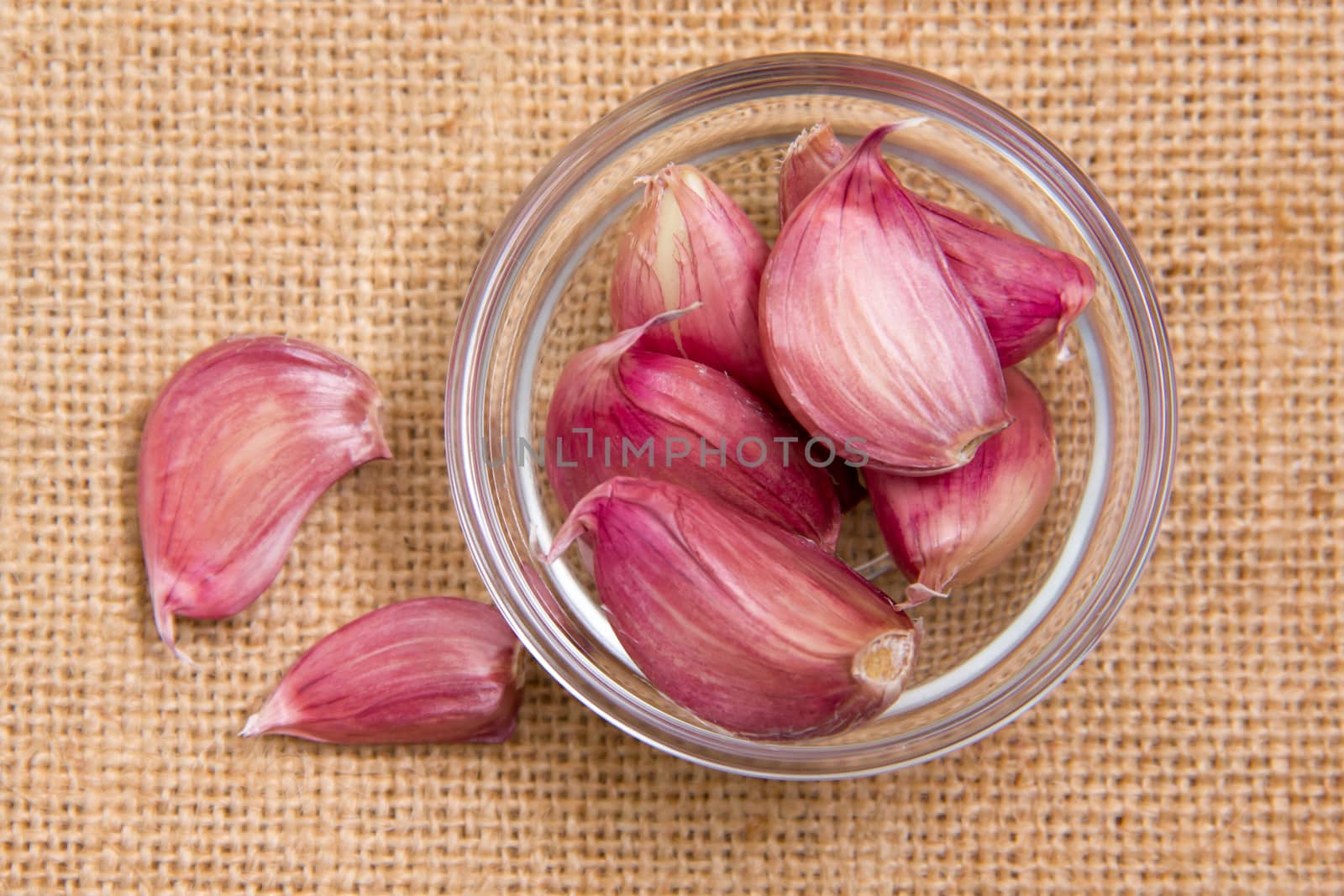 Garlic in glass bowl on placemat jute seen from above