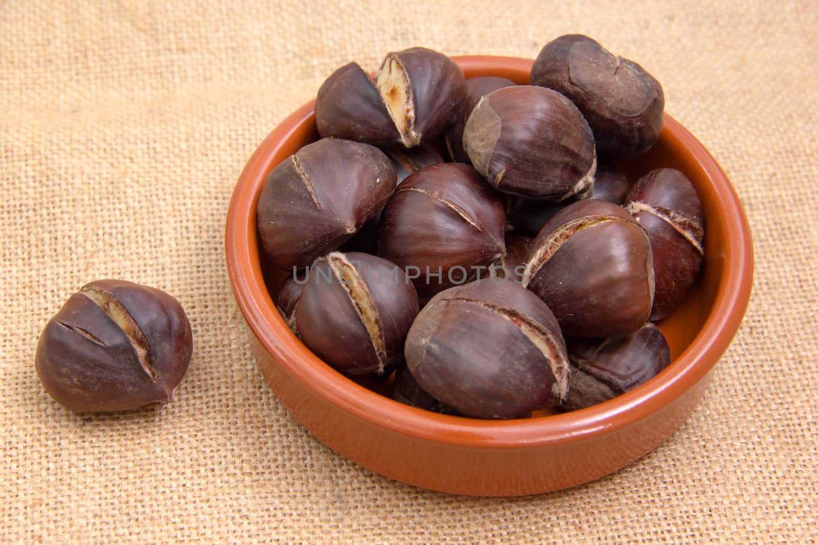 Roasted chestnuts in bowl on placemat jute