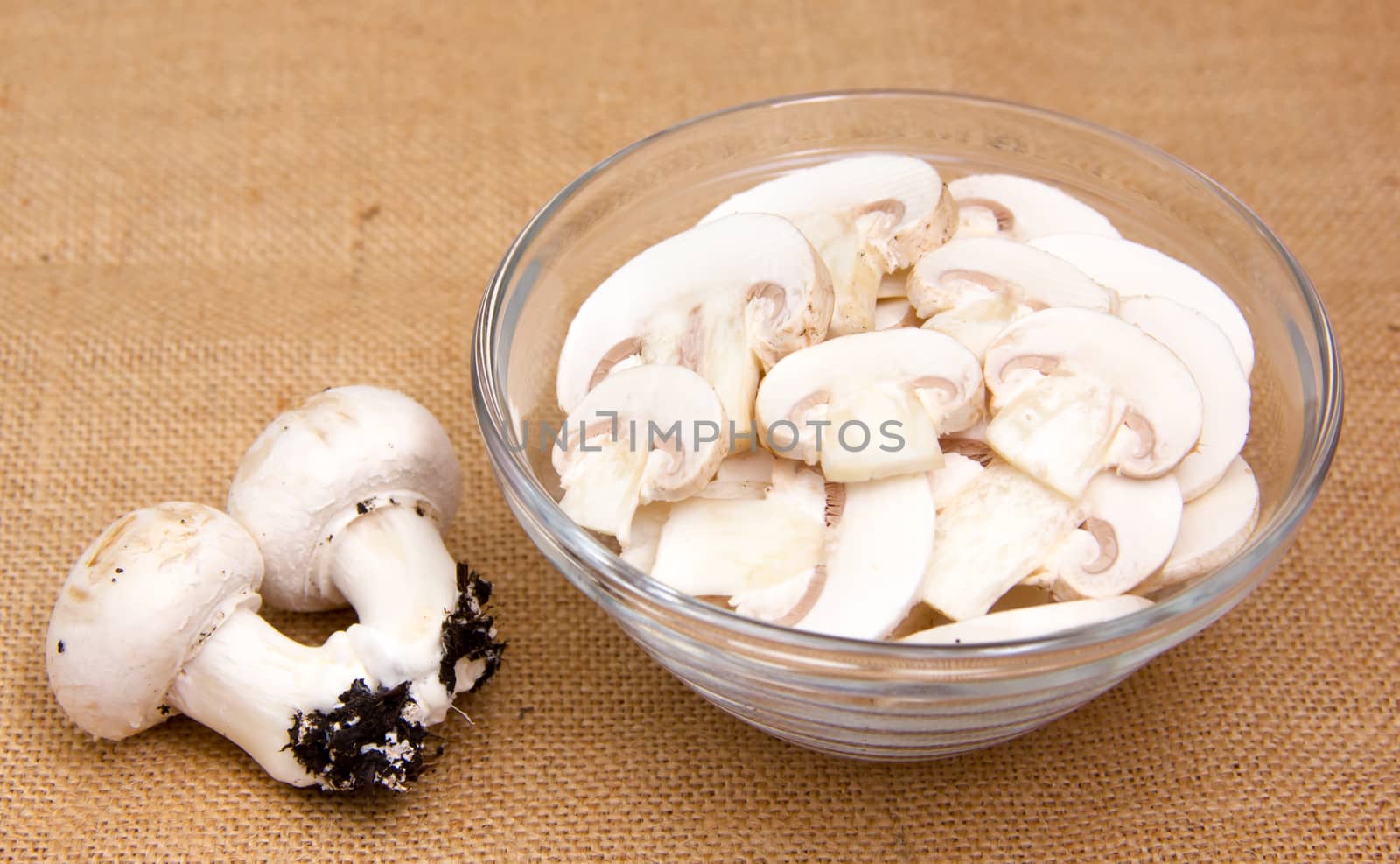 Sliced mushrooms in bowl on placemat jute