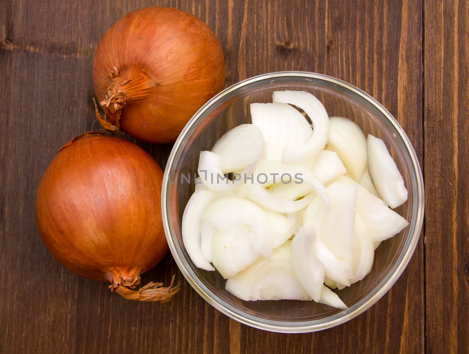 Sliced onion on bowl on wooden table top view