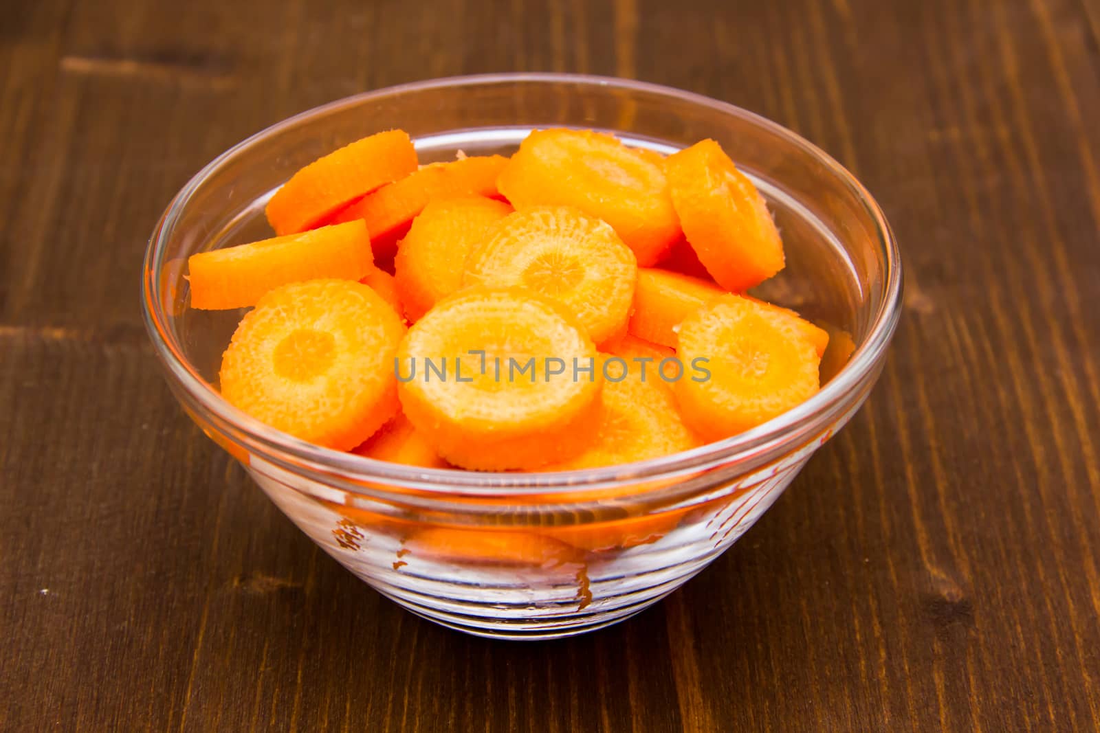 Carrot slices on bowl on wooden table