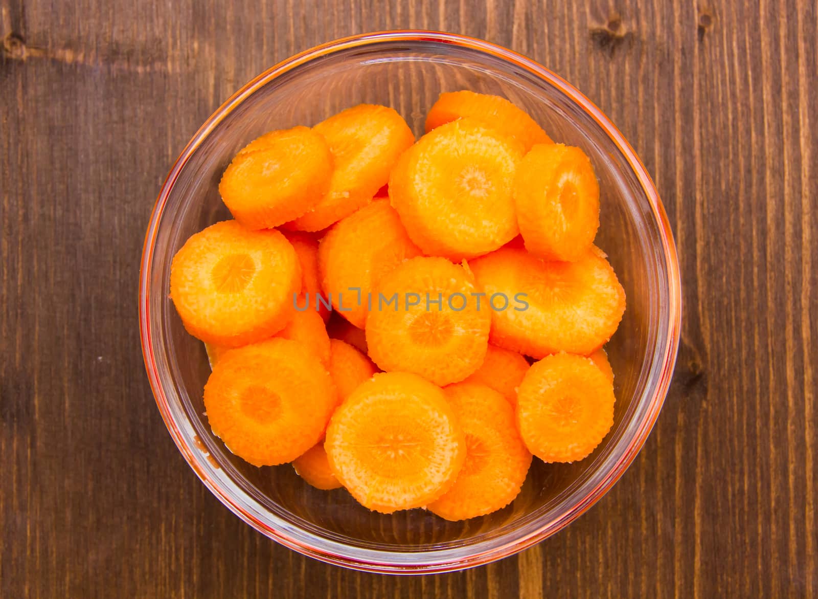 Carrot slices on bowl on wooden table top views