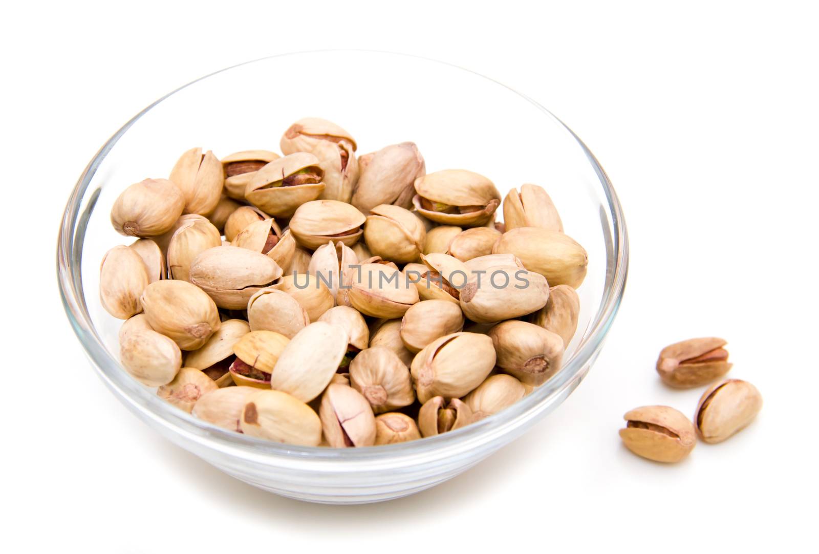 Pistachios on glass bowl on white background