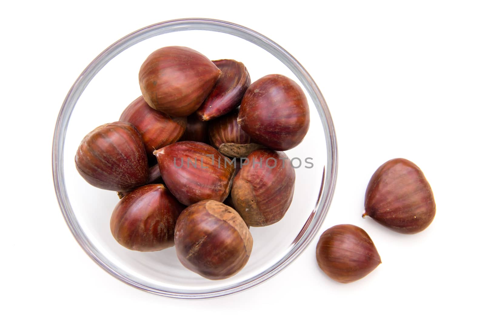 Glass bowl with chestnuts on white background top view