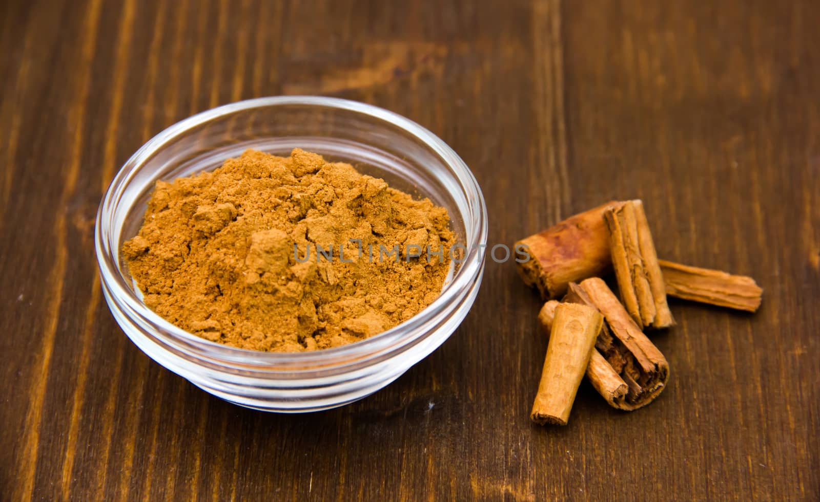 Glass bowl with cinnamon on wooden table