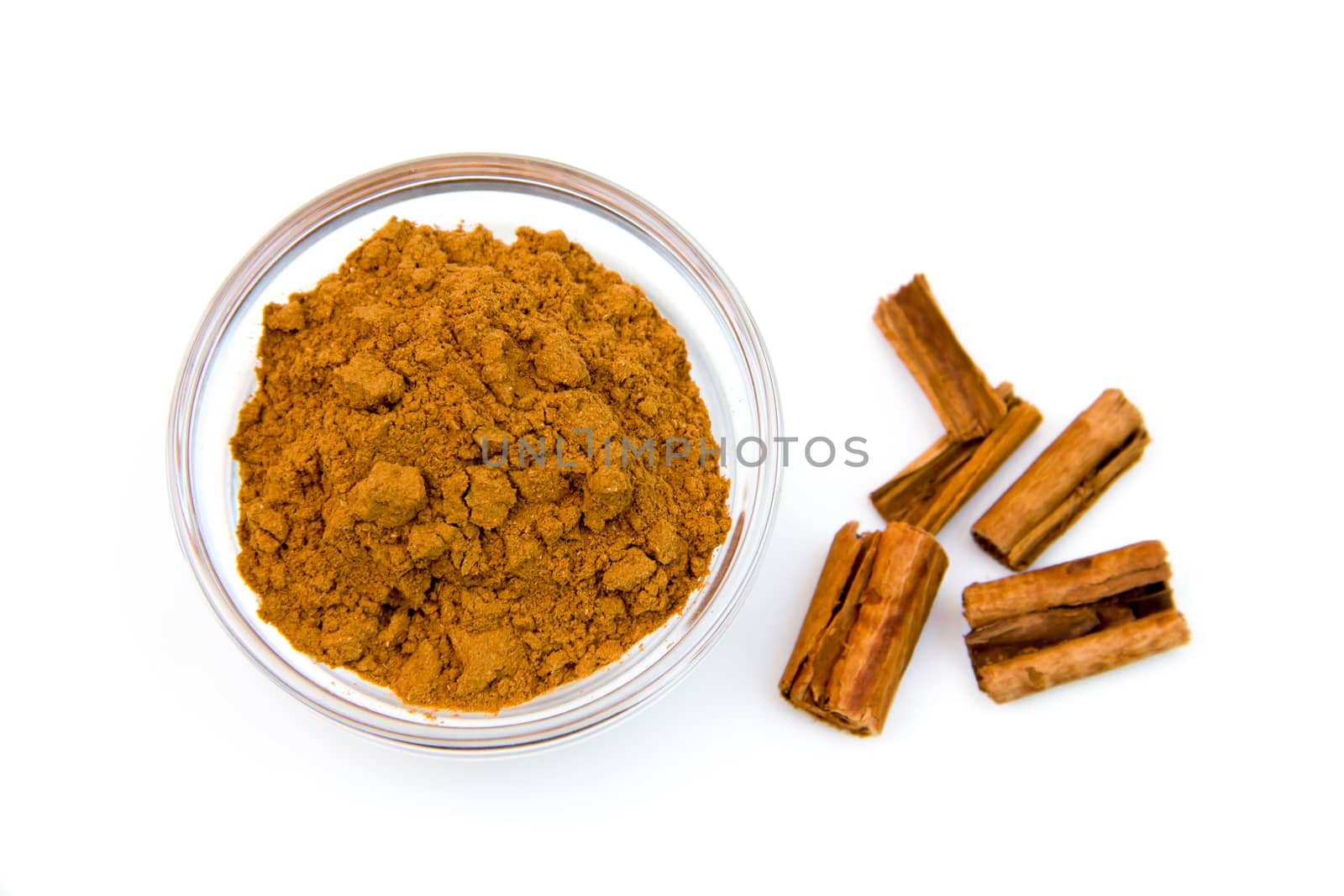 Glass bowl with cinnamon on white background top view
