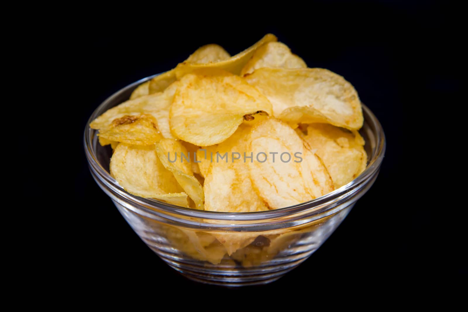 Bowl with potato chips on a black background