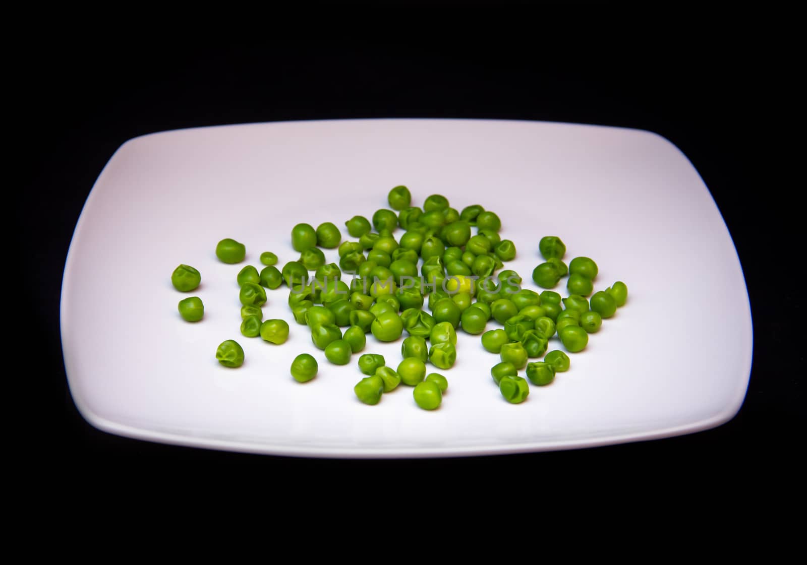 Plate with peas on a black background
