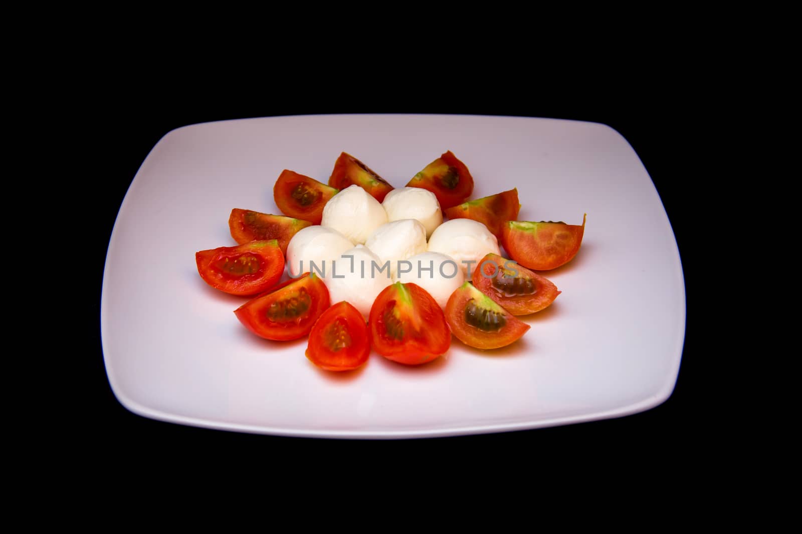 Plate with mozzarella and tomato on black by spafra