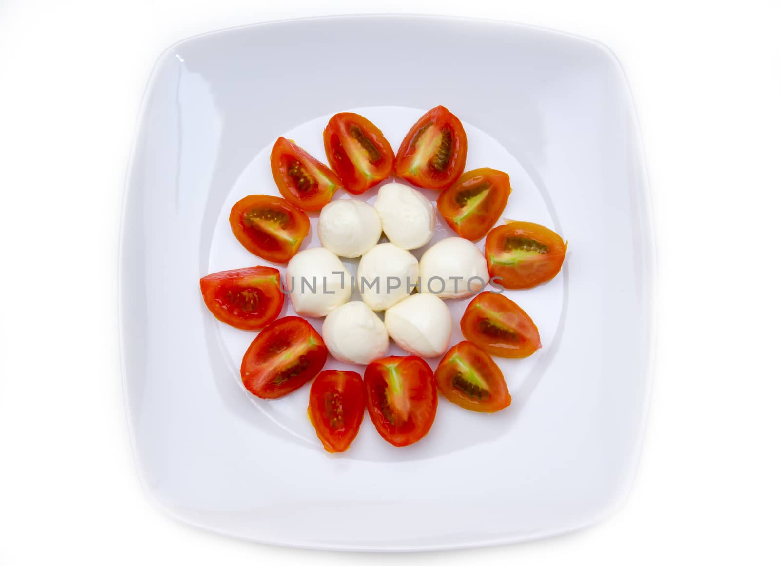 Plate with mozzarella and tomato on white background seen from above