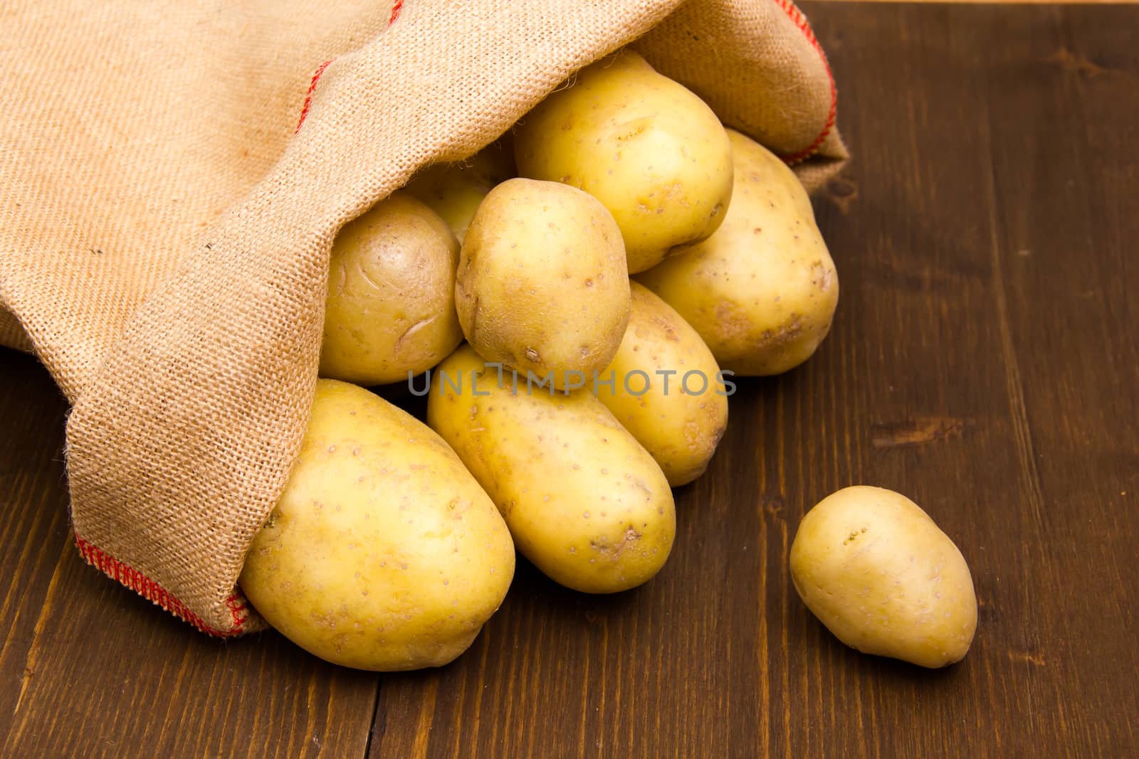 Sack of potatoes on wooden table seen up close