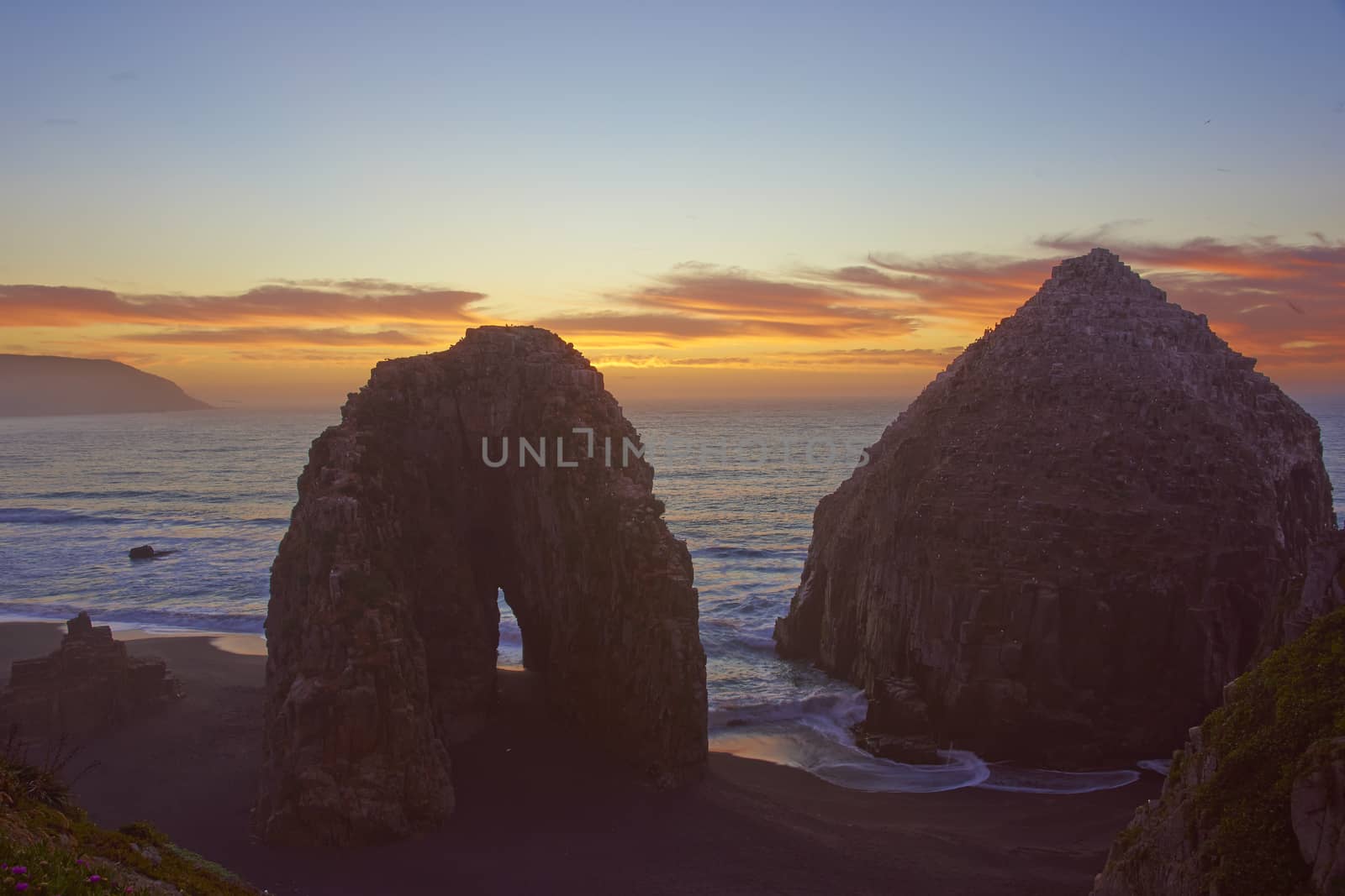 Colourful sunset over the pacific ocean at the coastal town of Constitucion in Maule, Chile. In the foreground are the Rocas de los Calabocillos, which are home to thousands of seabirds.