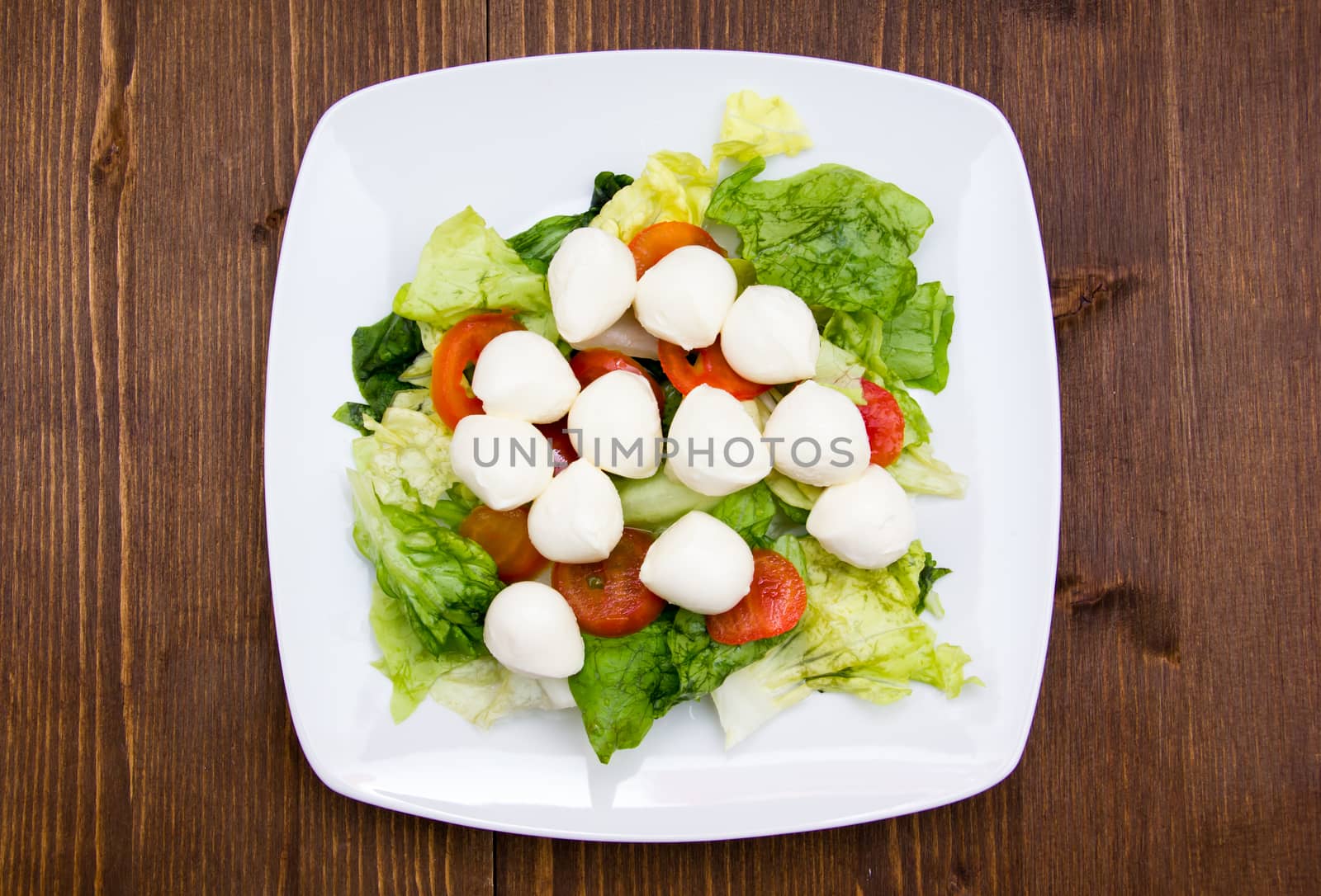 Salad with tomatoes and mozzarella on wooden table top view