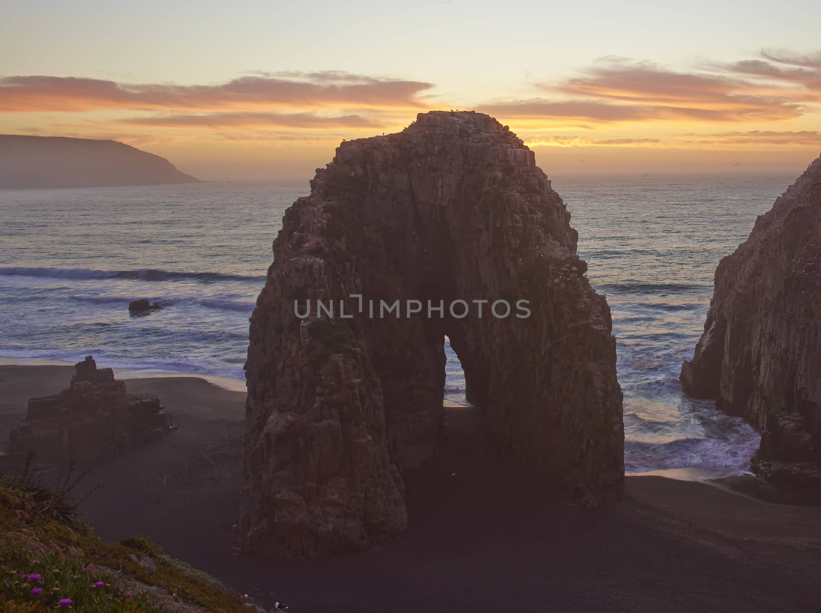 Colourful sunset over the pacific ocean at the coastal town of Constitucion in Maule, Chile. In the foreground are the Rocas de los Calabocillos, which are home to thousands of seabirds.