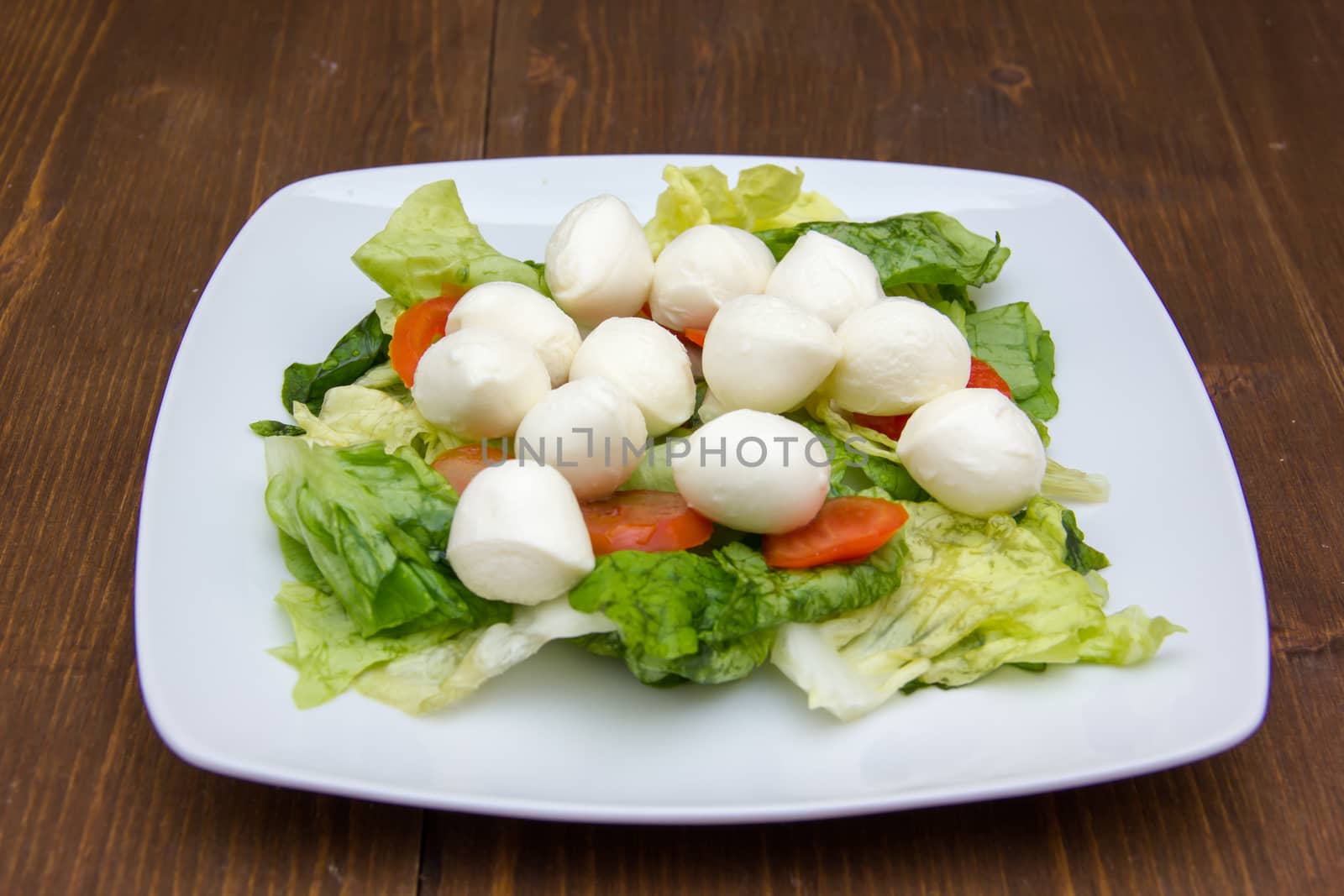 Salad with tomatoes and mozzarella on wooden table